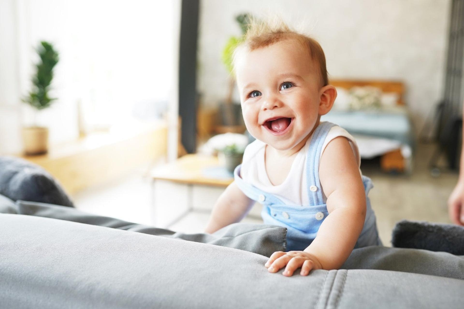 Cute baby boy climbing a couch and smiling
