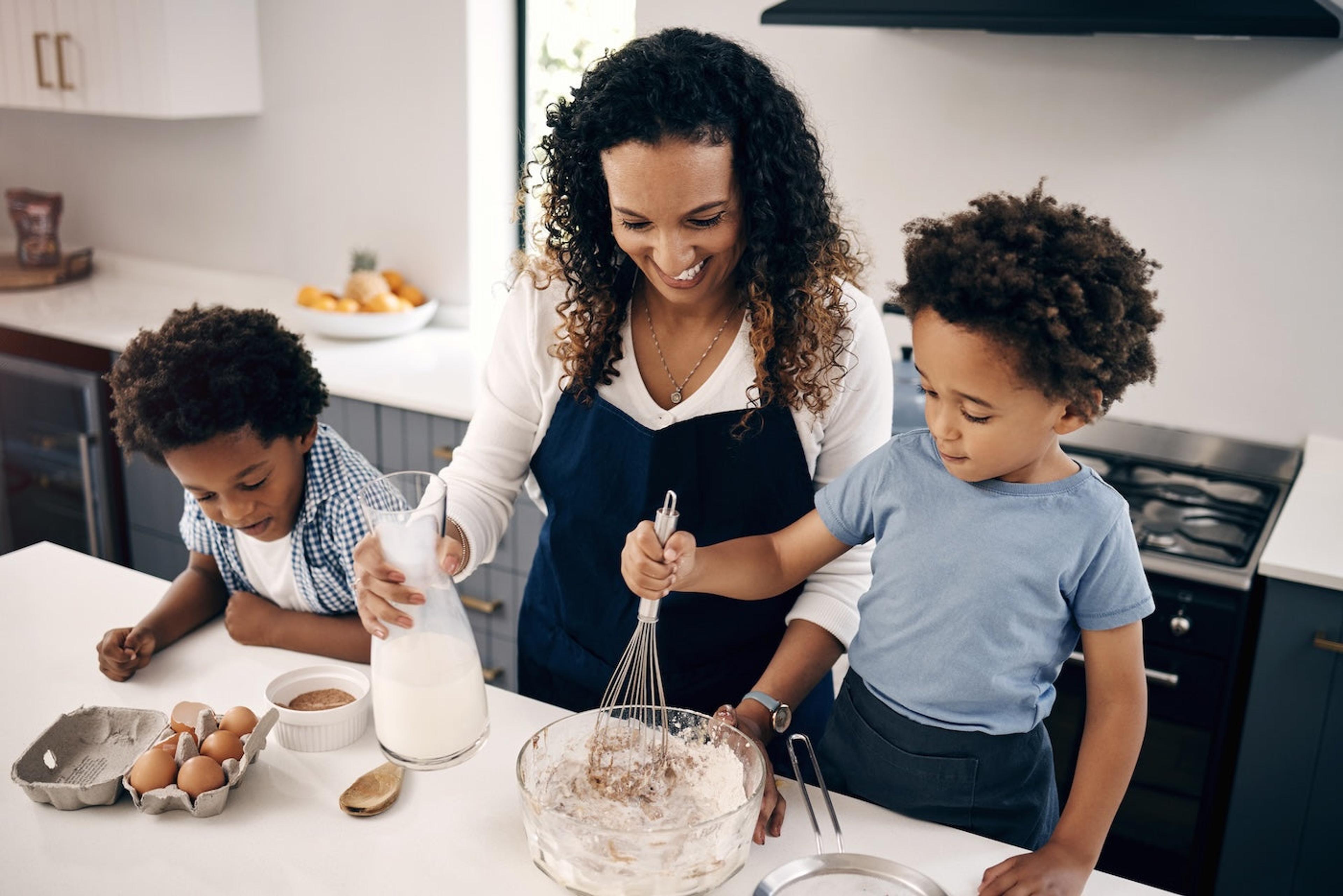 A mom and two kids cook together in the kitchen