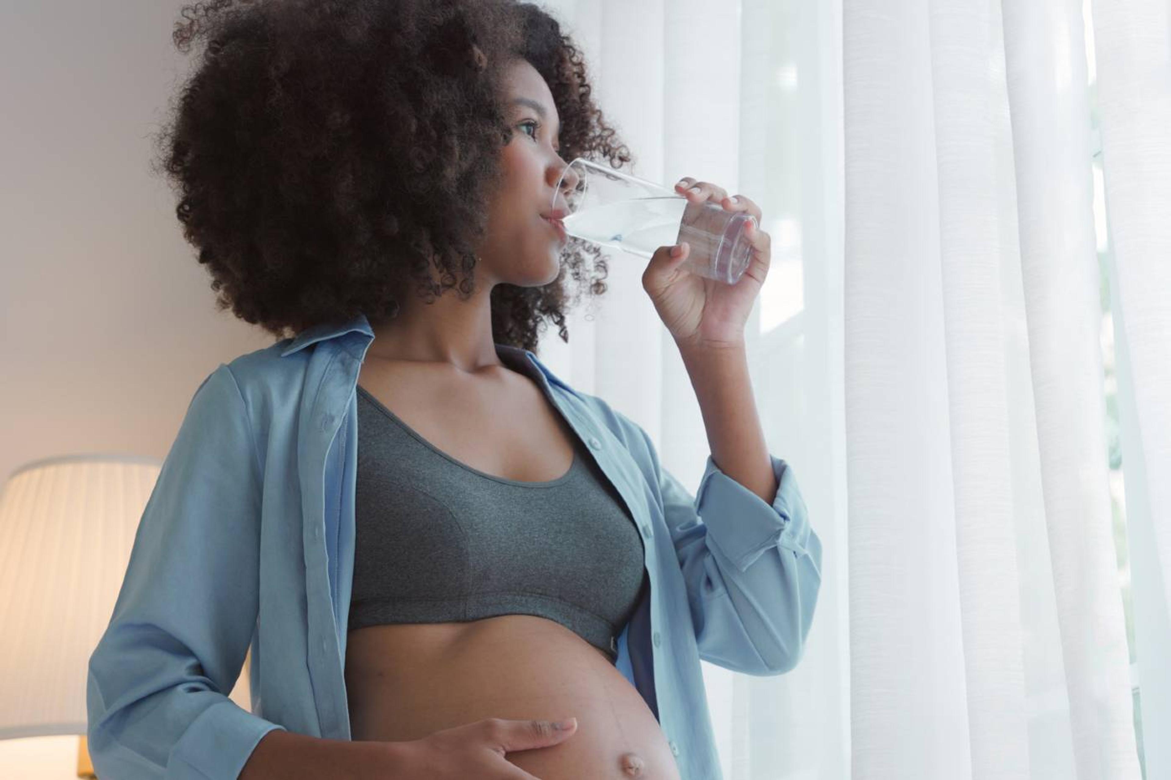 Pregnant woman drinking water to stay hydrated during pregnancy