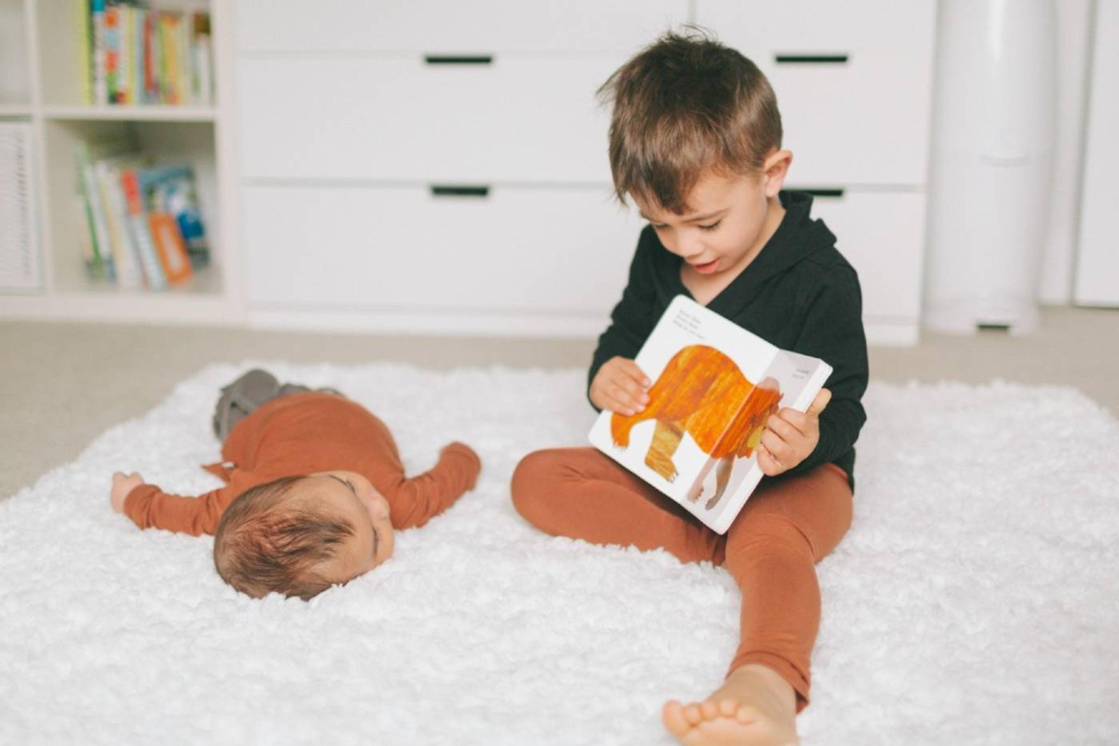 Toddler reading animal book to baby