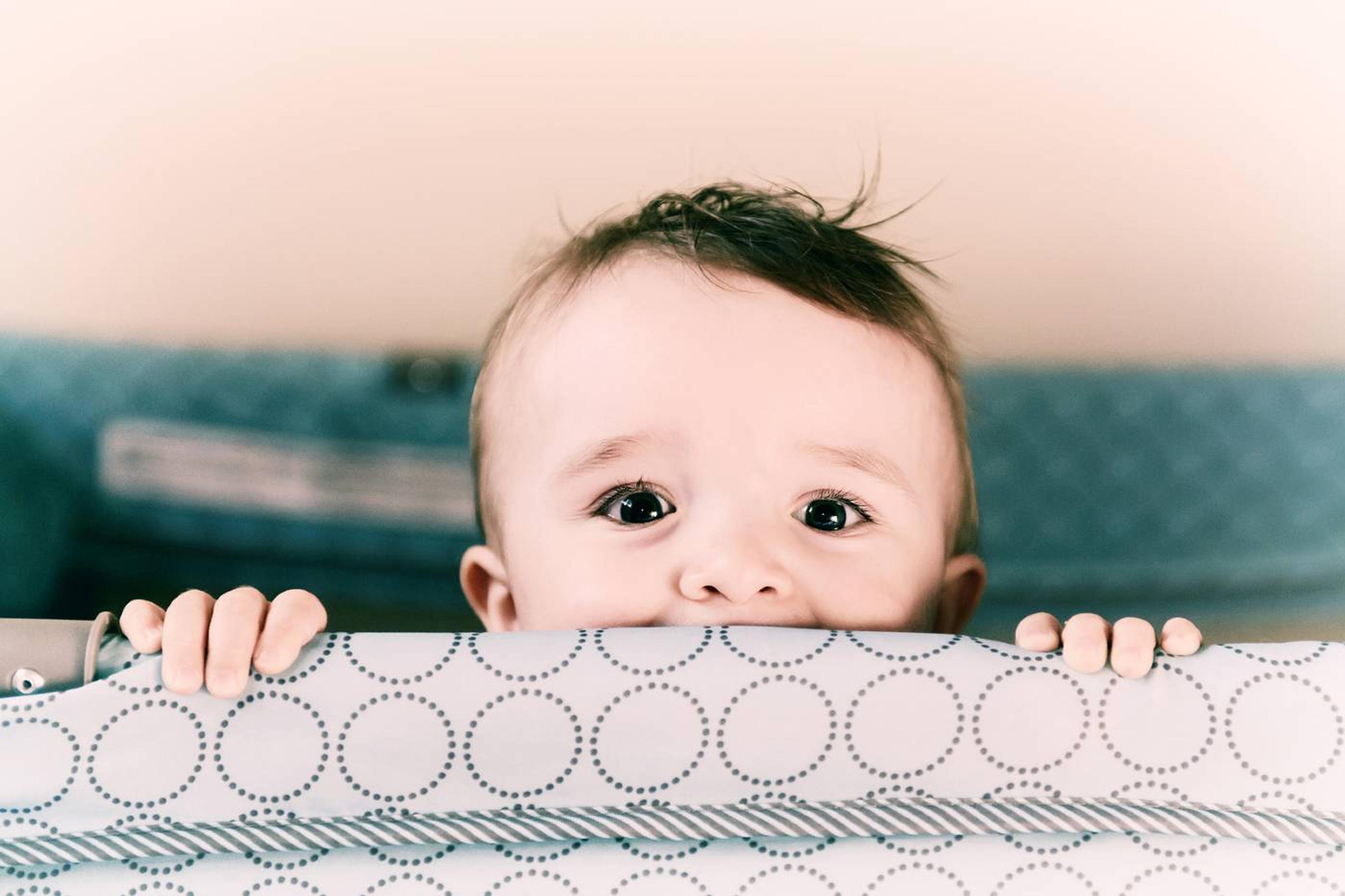 Baby peeking over travel crib