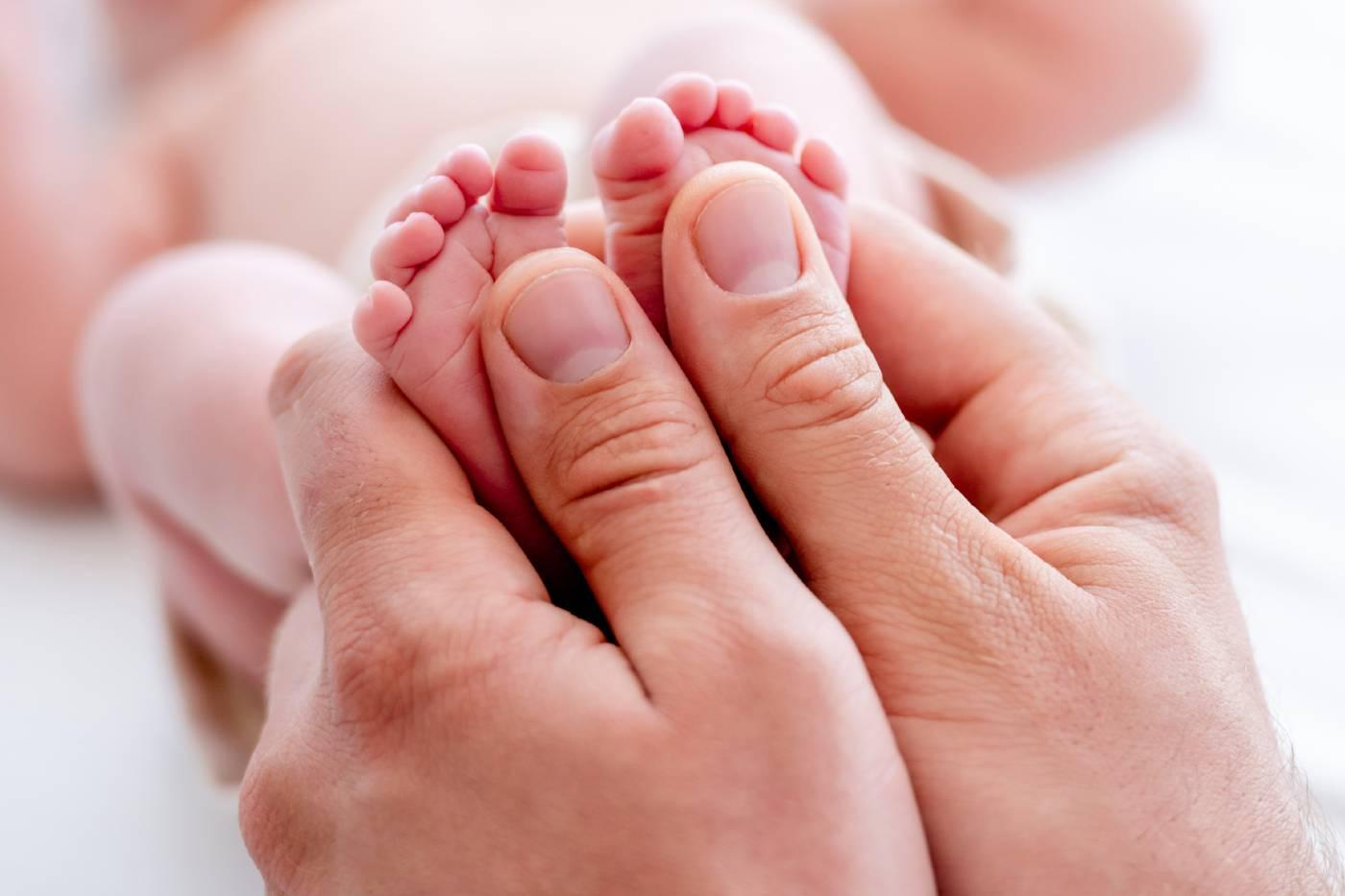 Parent holding baby's feet looking for signs of hair tourniquet syndrome