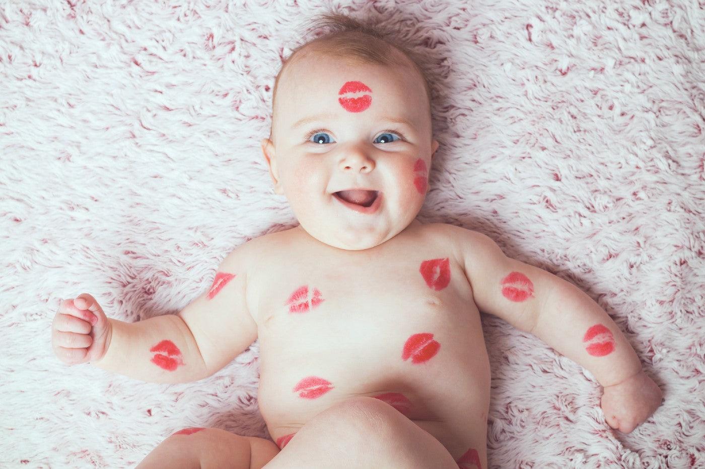 A cute baby covered in lipstick kisses