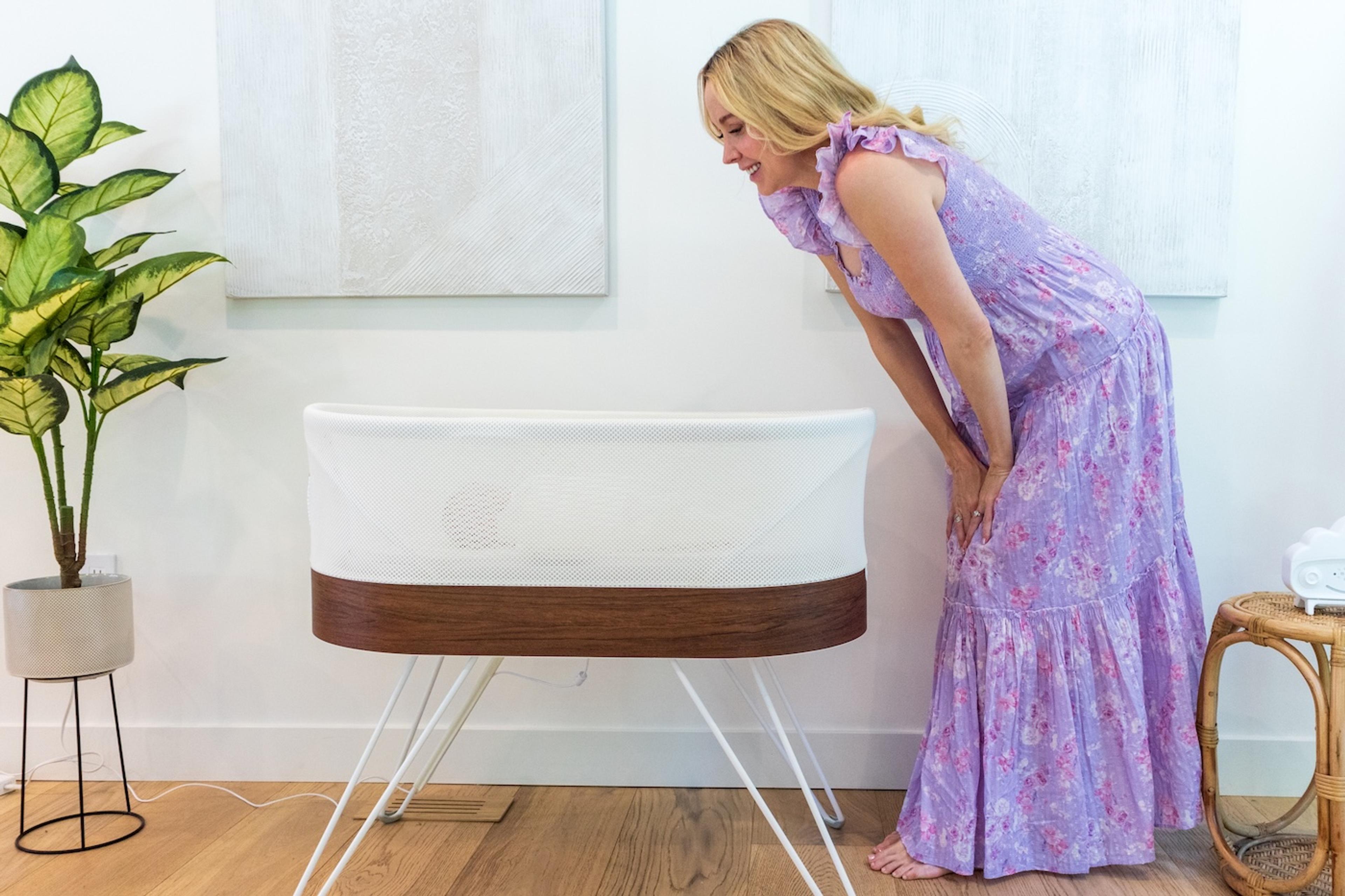 A mom looks into a SNOO Smart Sleeper bassinet