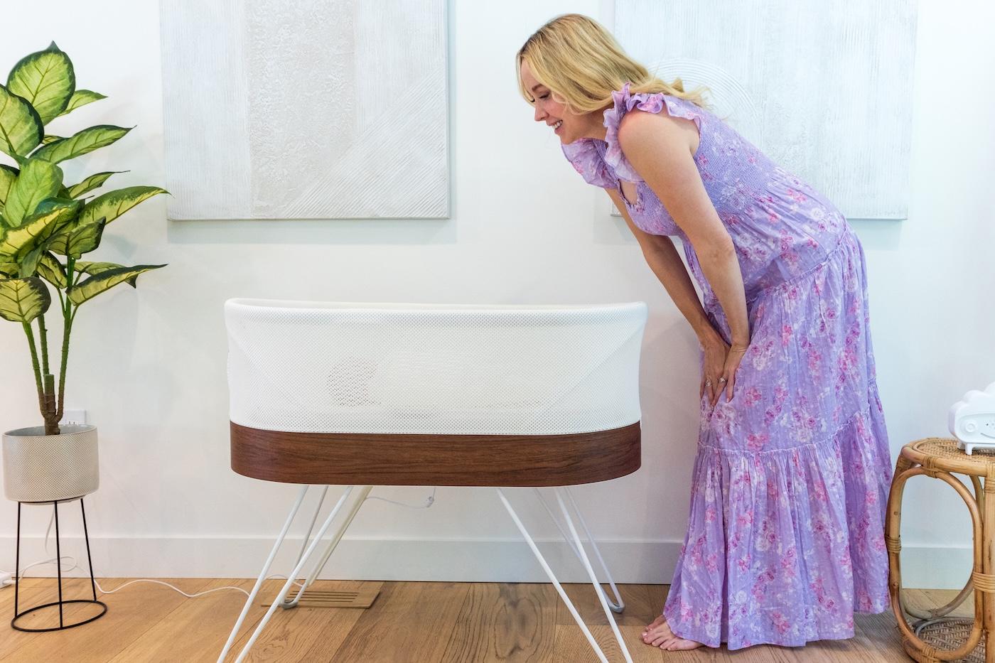 A mom looks into a SNOO Smart Sleeper bassinet