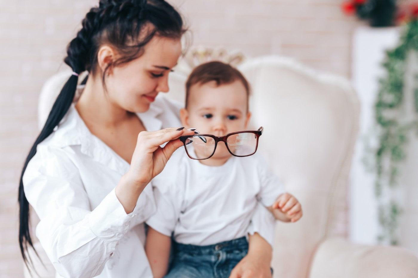 A mom puts a pair of glasses over a baby's face