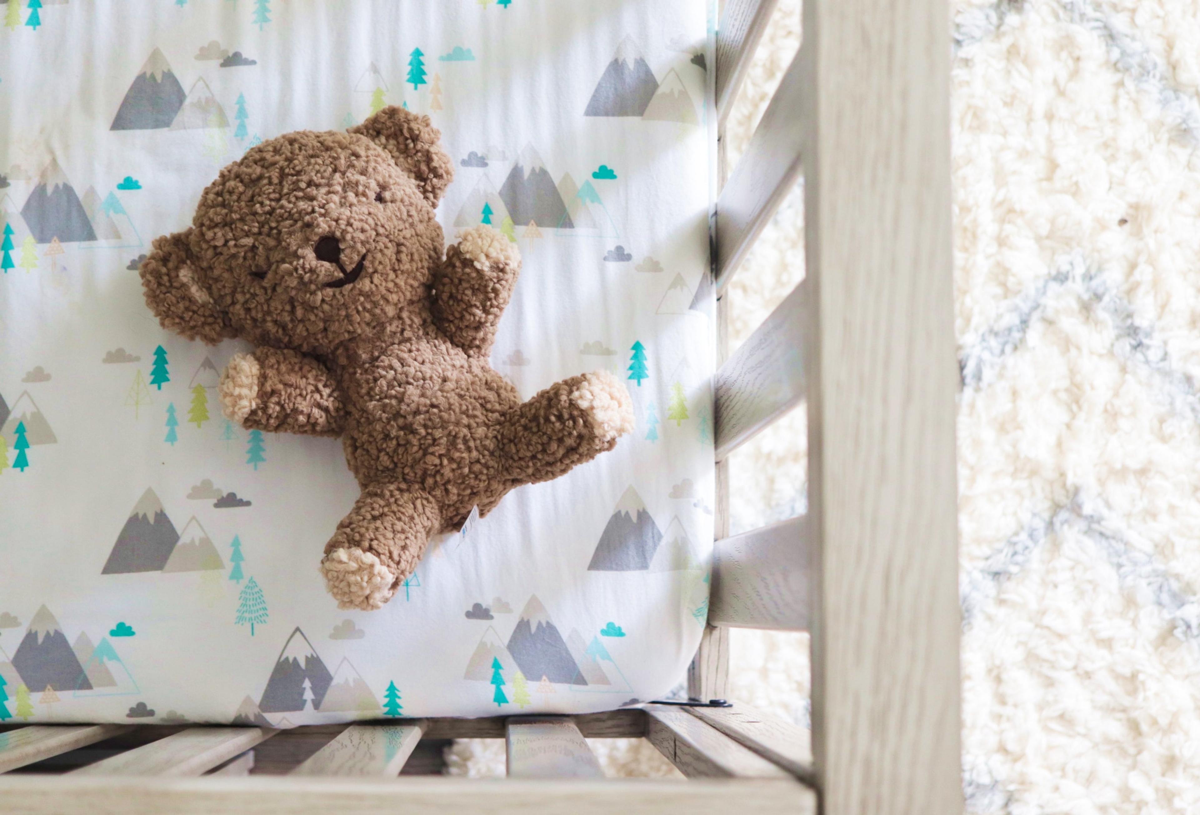A SNOObear teddy bear in a baby crib