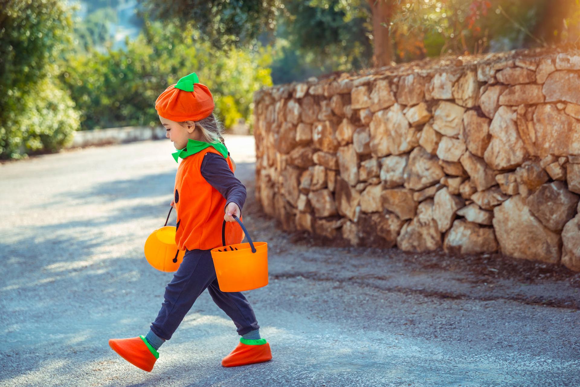 Little girl trick or treating dressed as a pumpkin