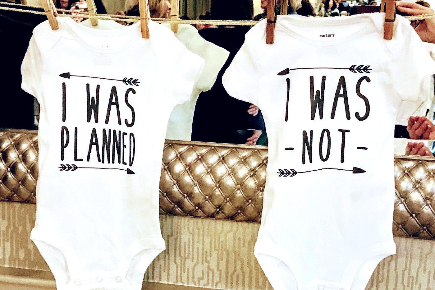 Baby onesies that say "I was planned" and "I was not" to announce a twin pregnancy