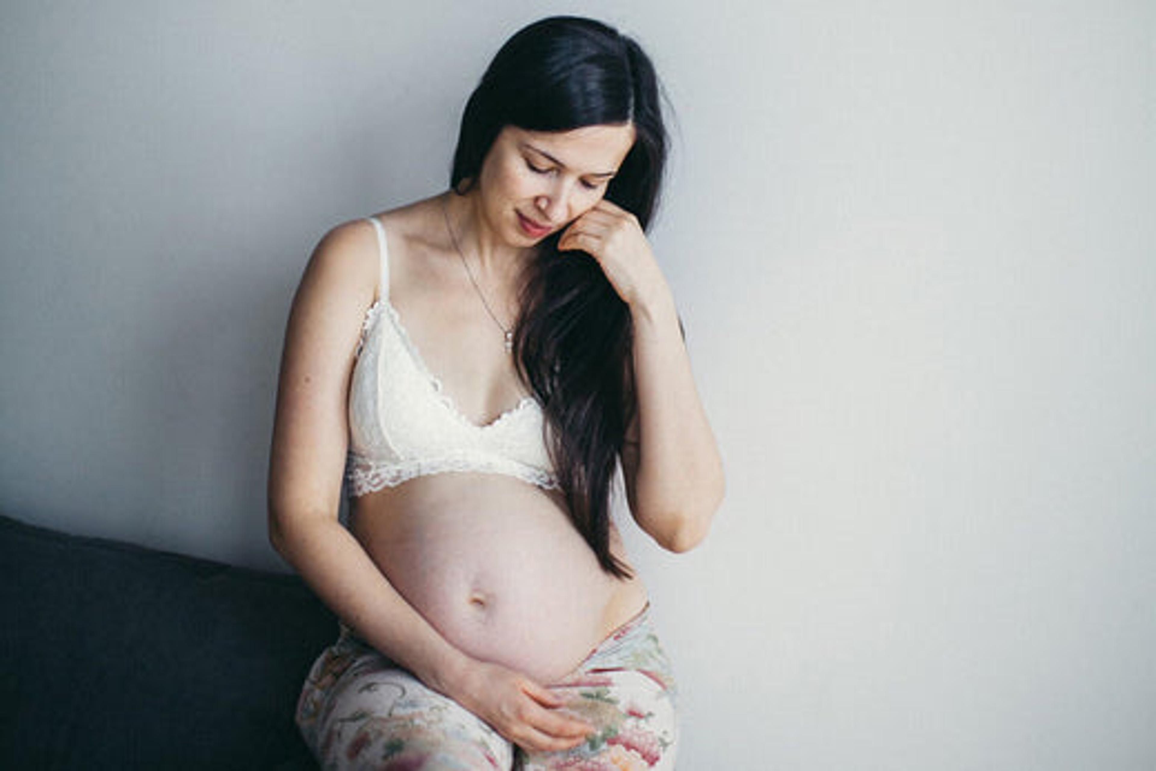 Woman looking at baby bump as she struggles with depression during pregnancy