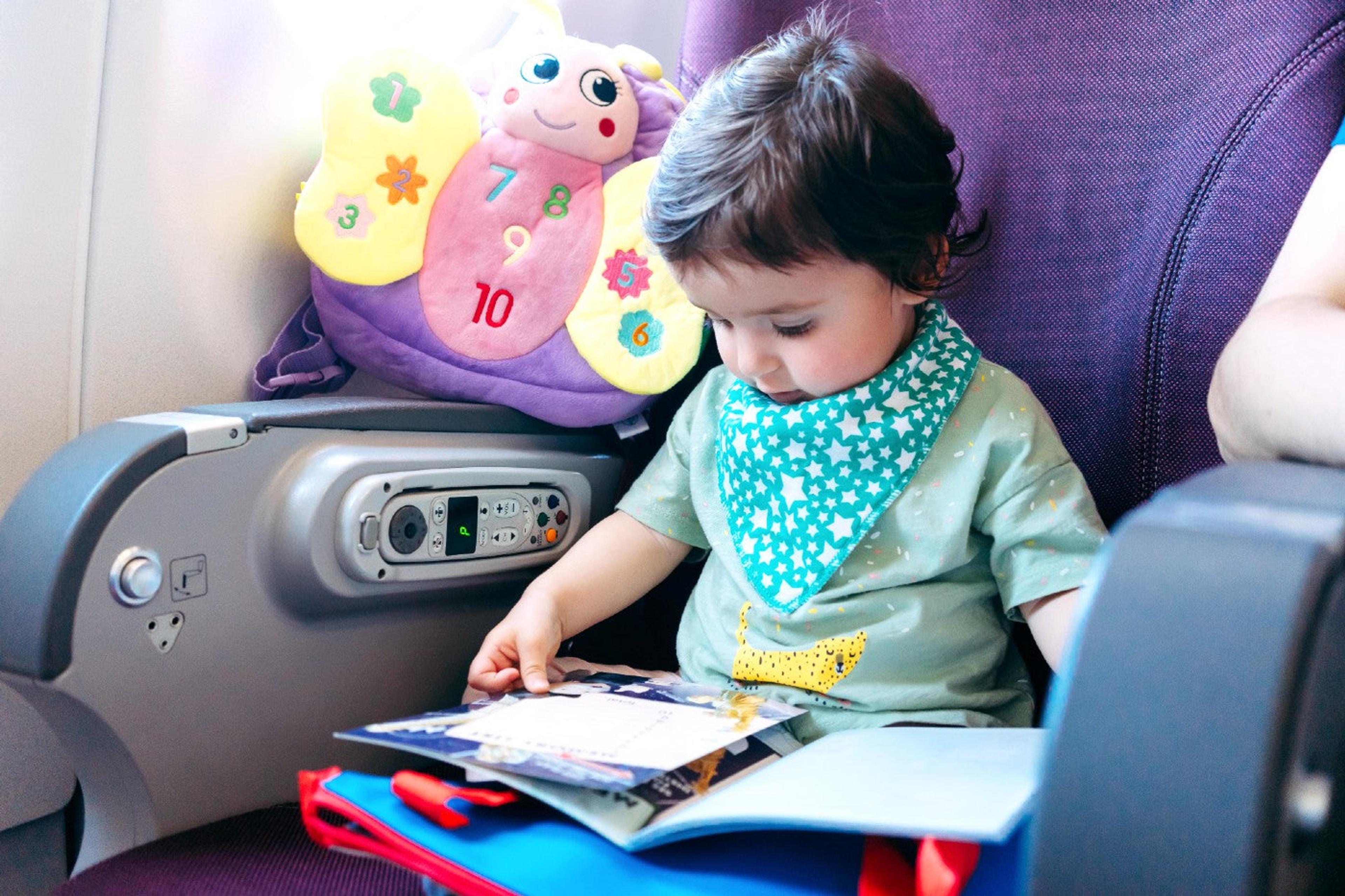 Toddler reads a busy book toy on an airplane