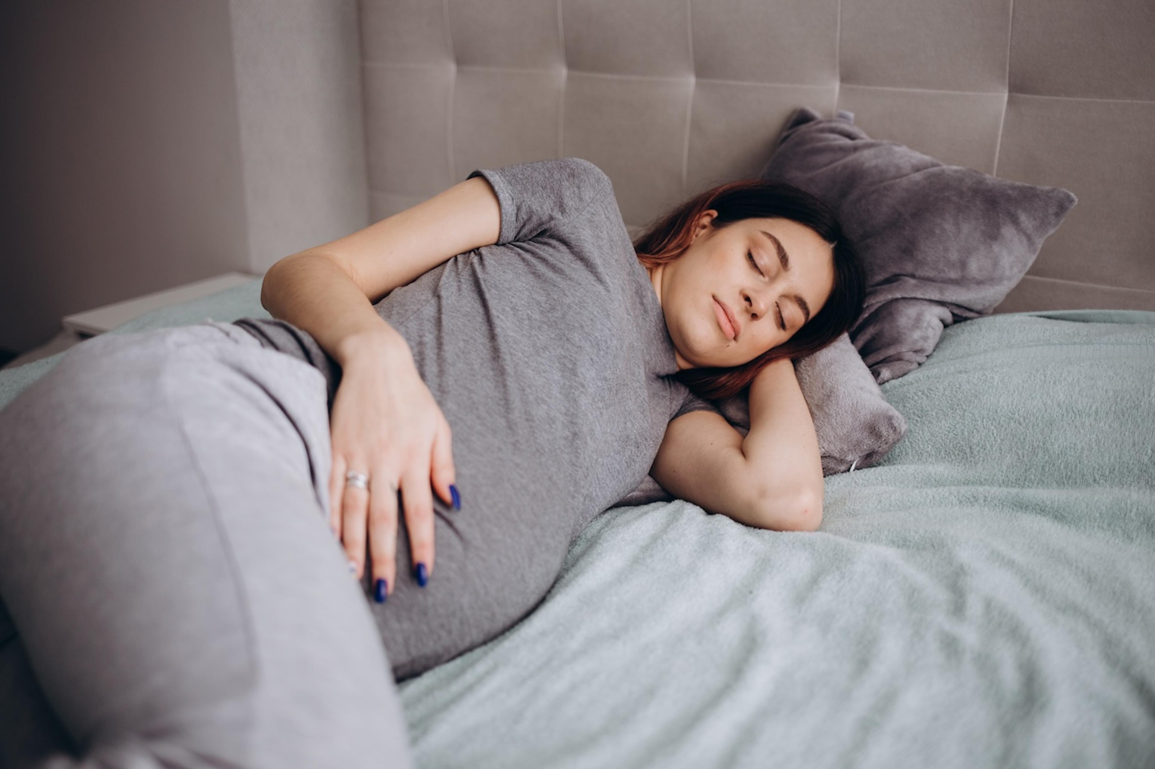 A pregnant woman struggles to get comfortable and contemplates sleeping on her stomach