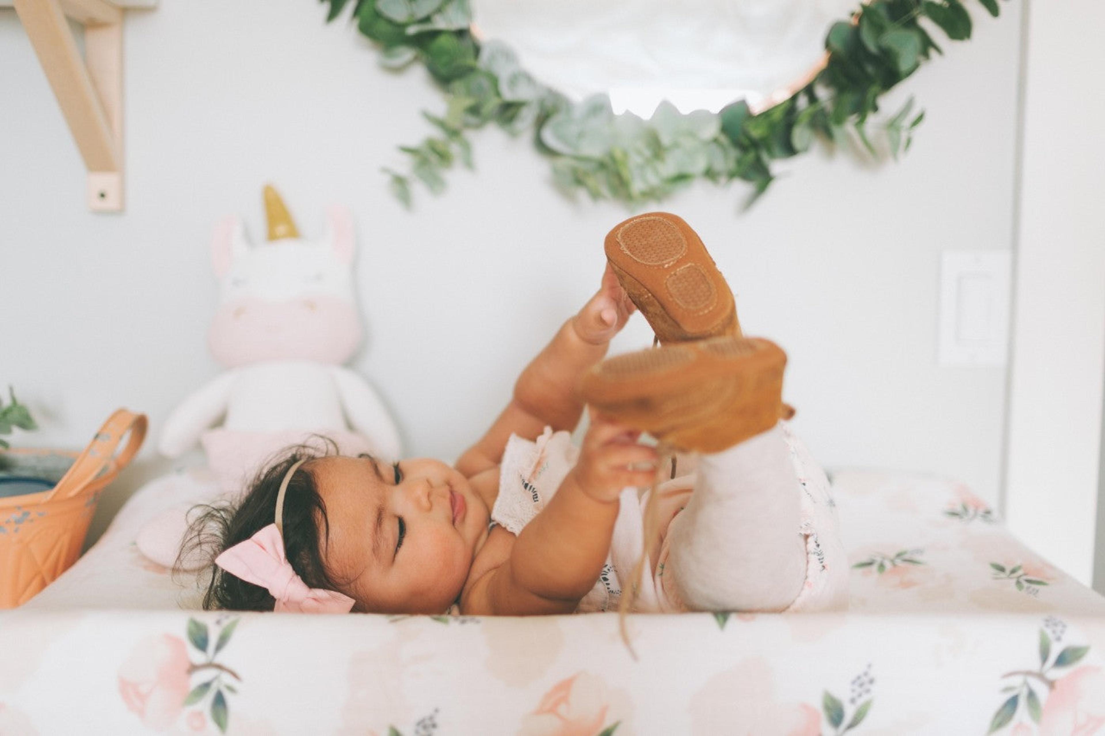 Cute baby girl laying on changing table grabbing at her feet. 