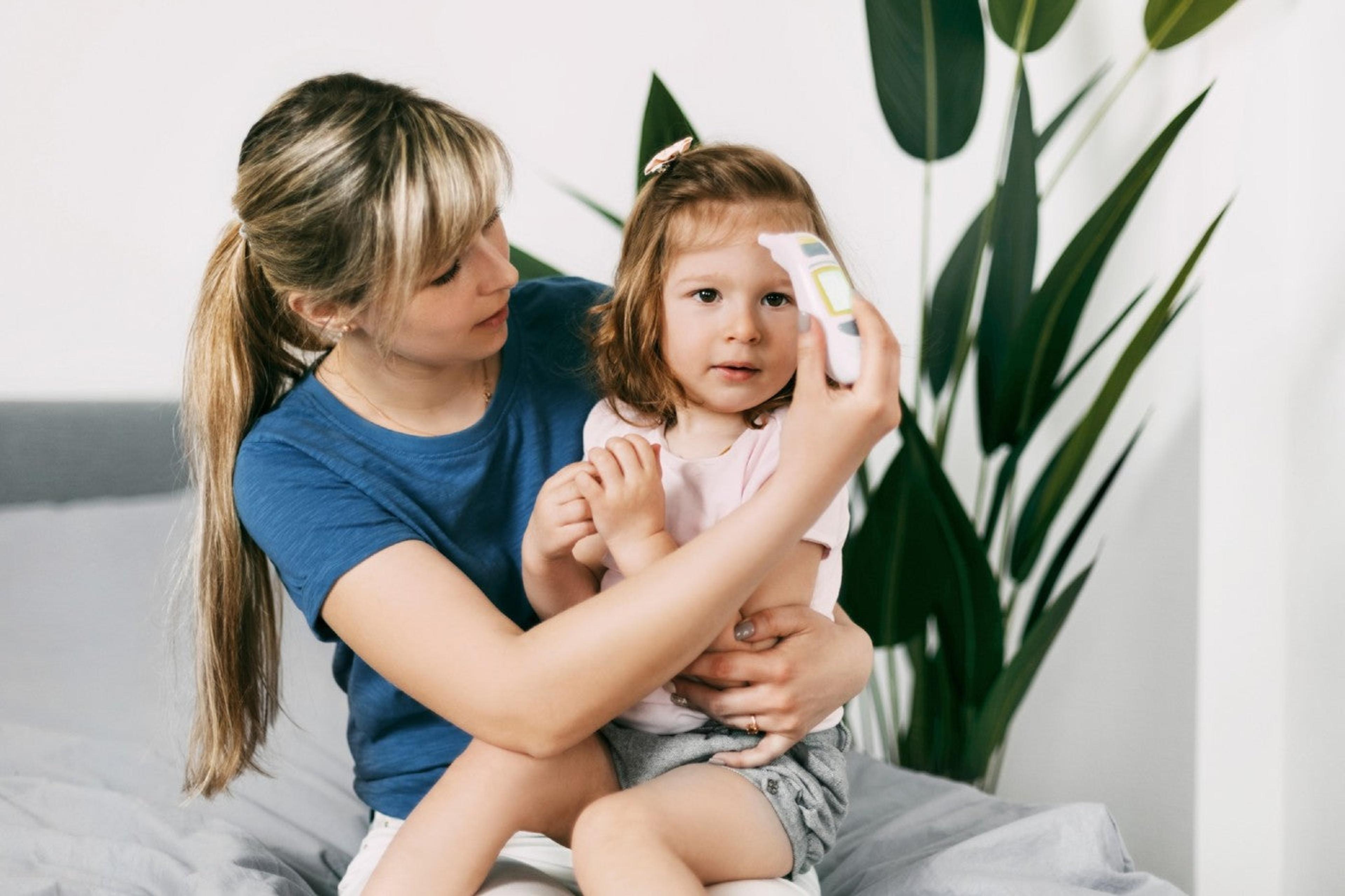 A mother takes her toddler's temperature