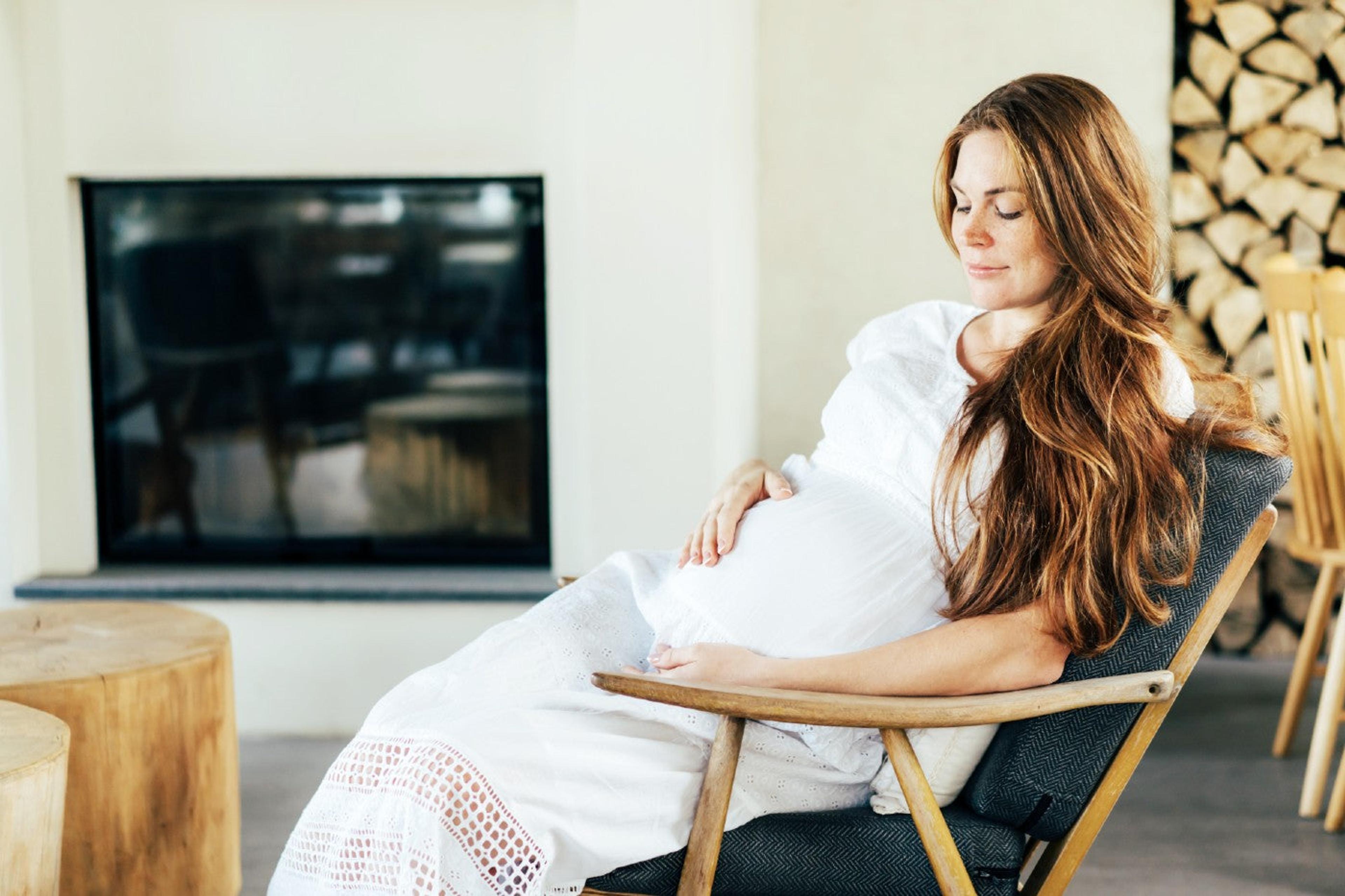 A pregnant woman sits in a Scandinavian-style chair