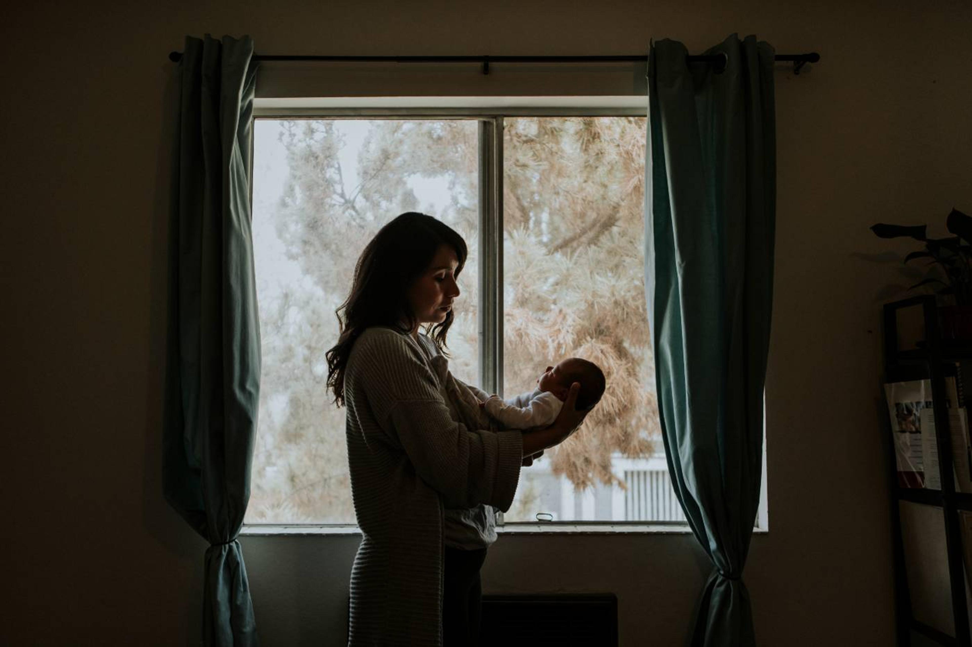 loneliness in parenthood: mom holding baby indoors