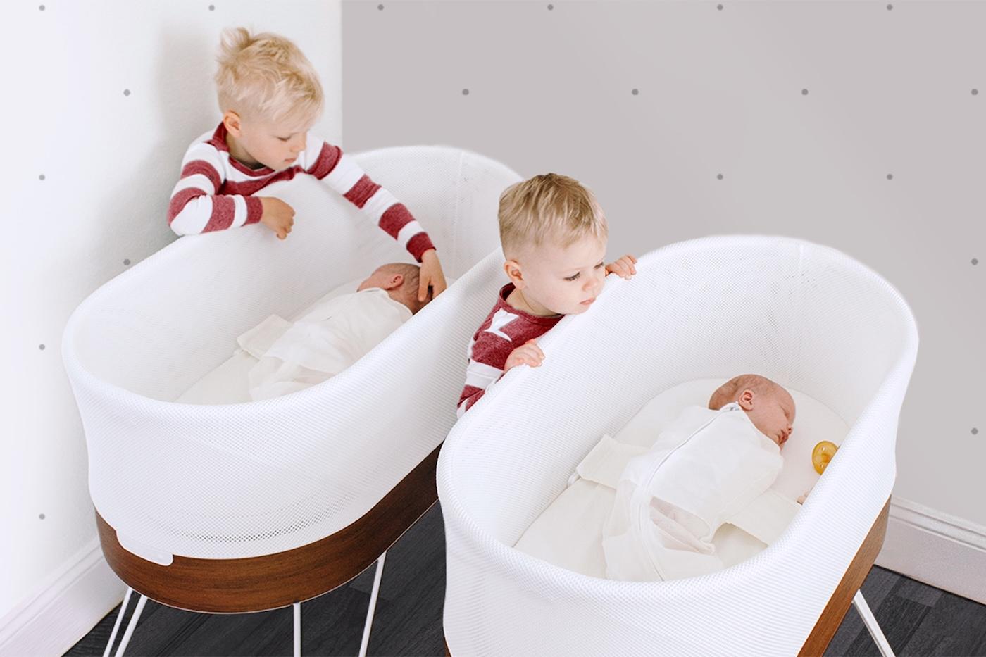 Brothers look at their twin baby siblings sleeping in SNOO
