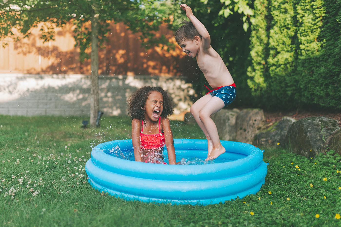 A girl and a boy toddler play outside in a kiddie pool for a fun summer activity