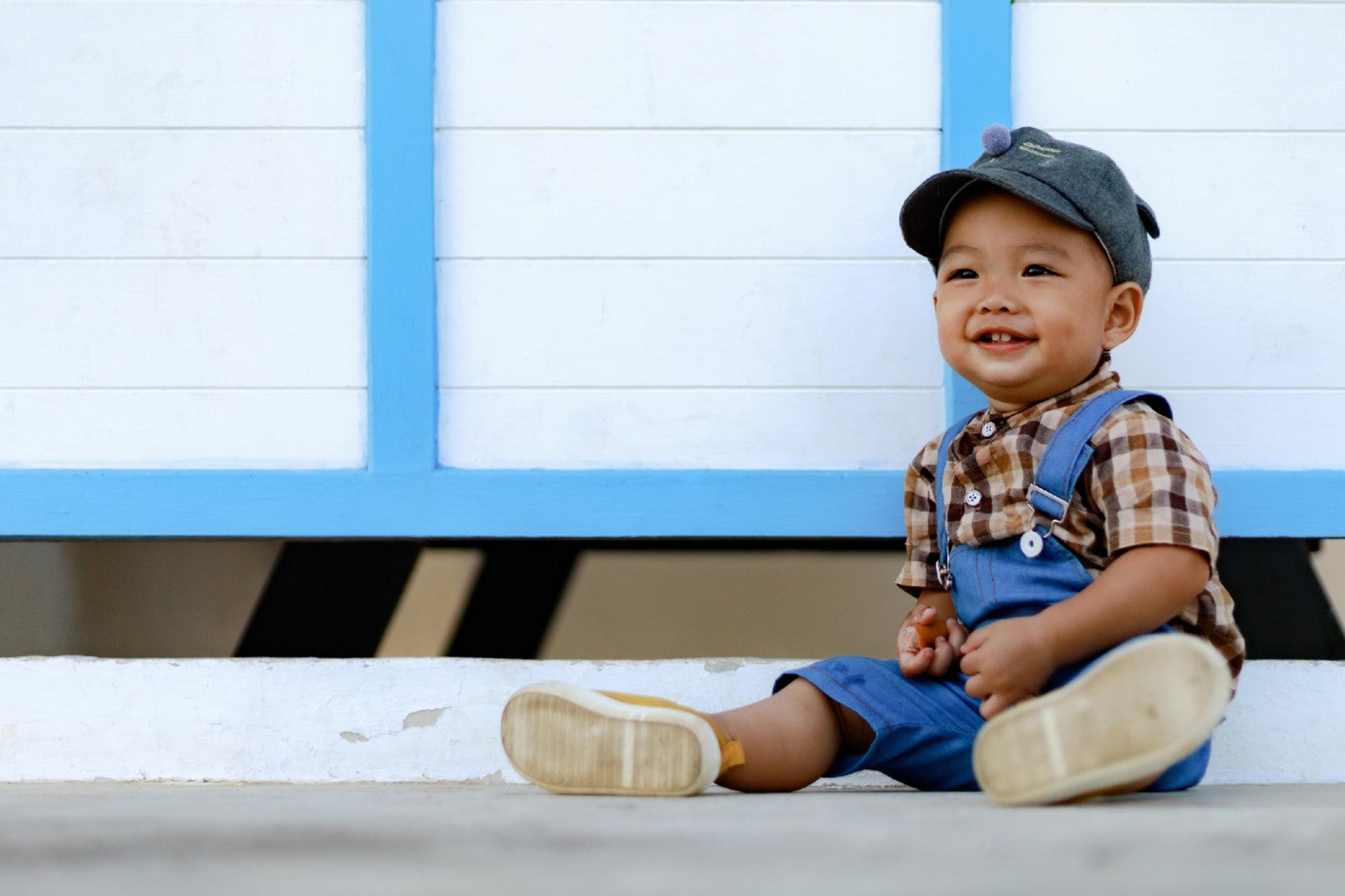 A 15-month-old baby boy sits and smiles