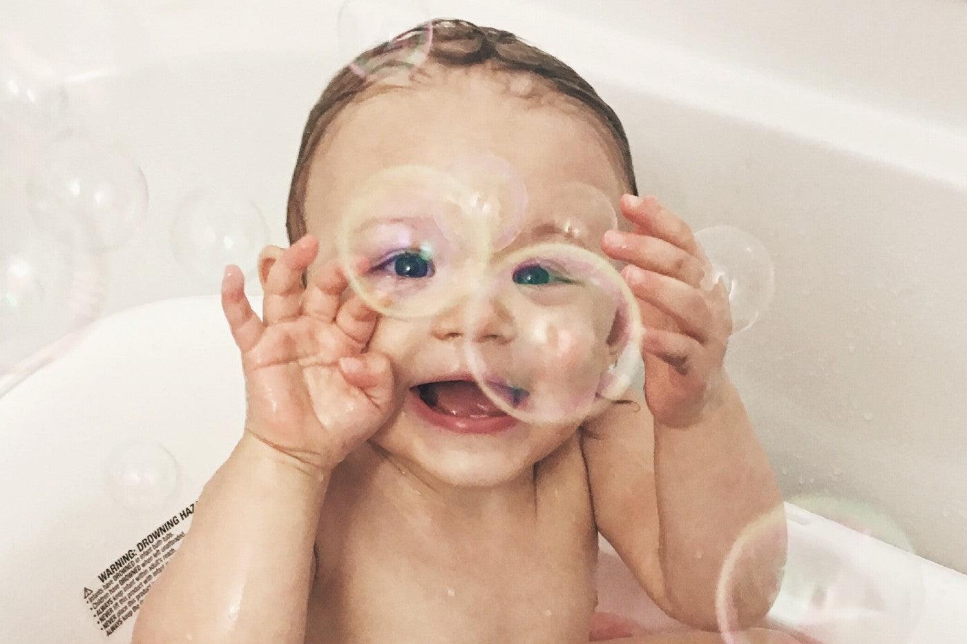 Toddler plays in the tub with bubbles
