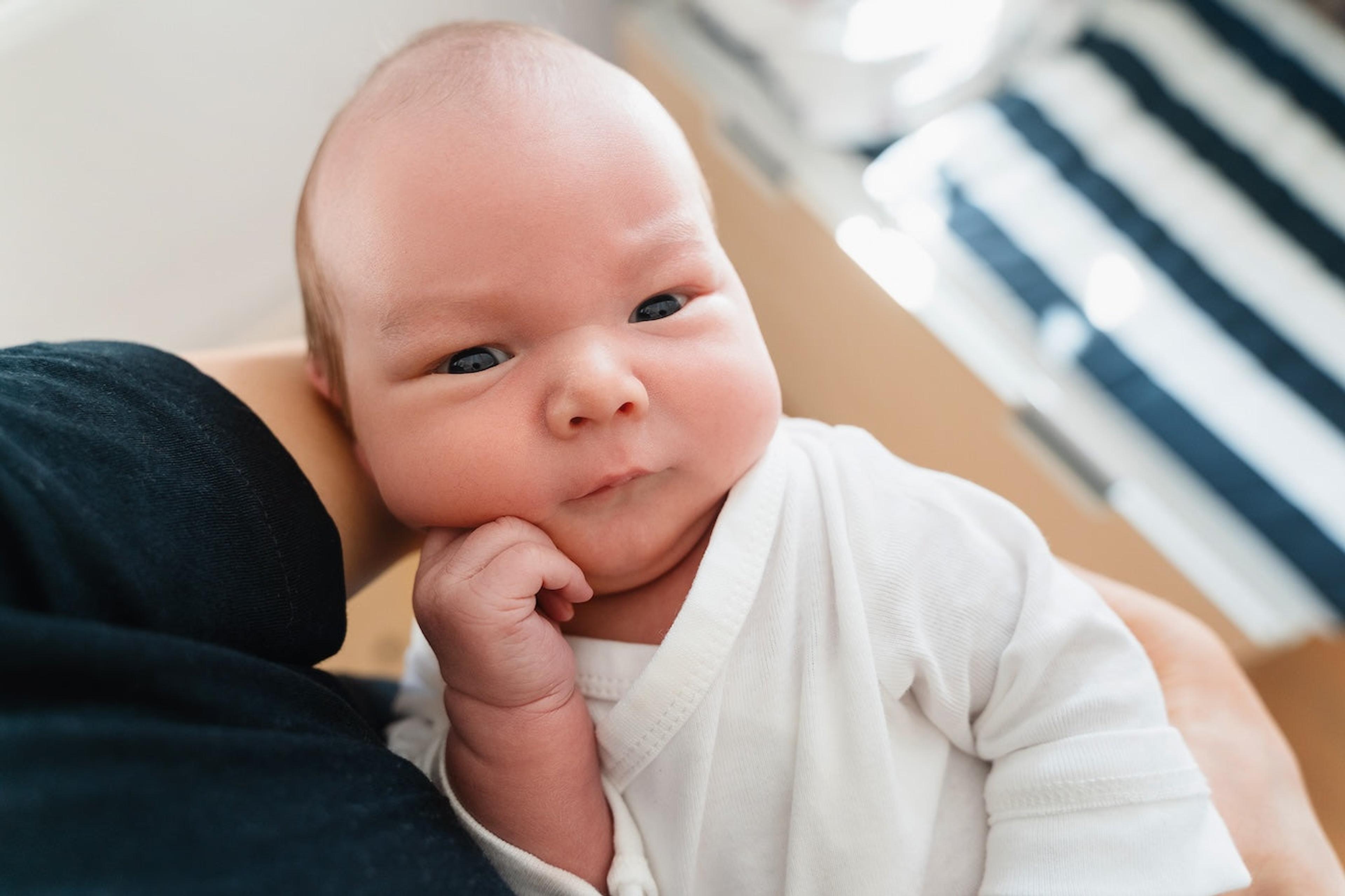 Wise-looking newborn baby with hand on chin