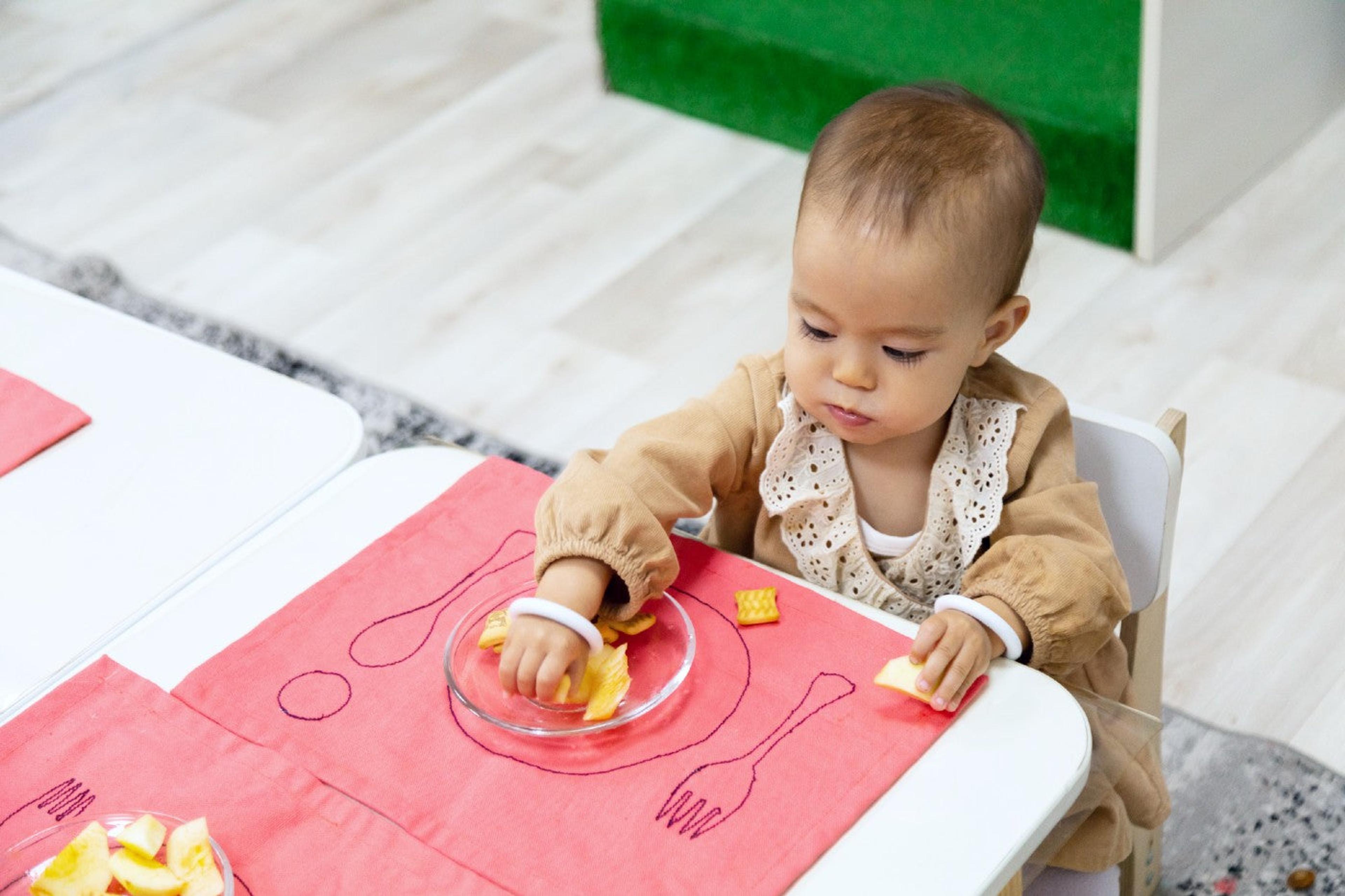 A young toddler eats at a small table