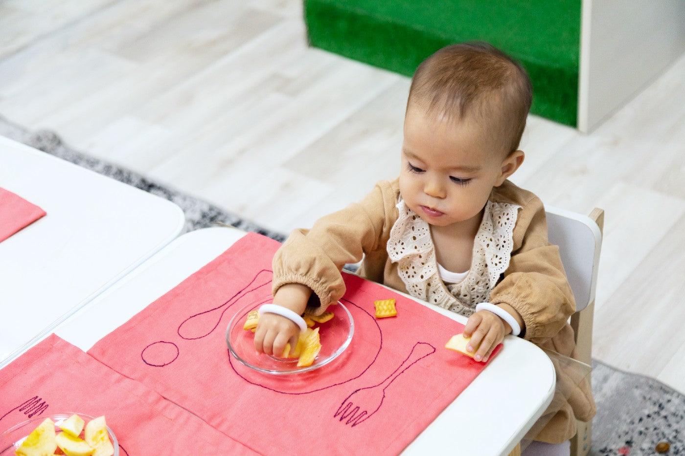 A young toddler eats at a small table