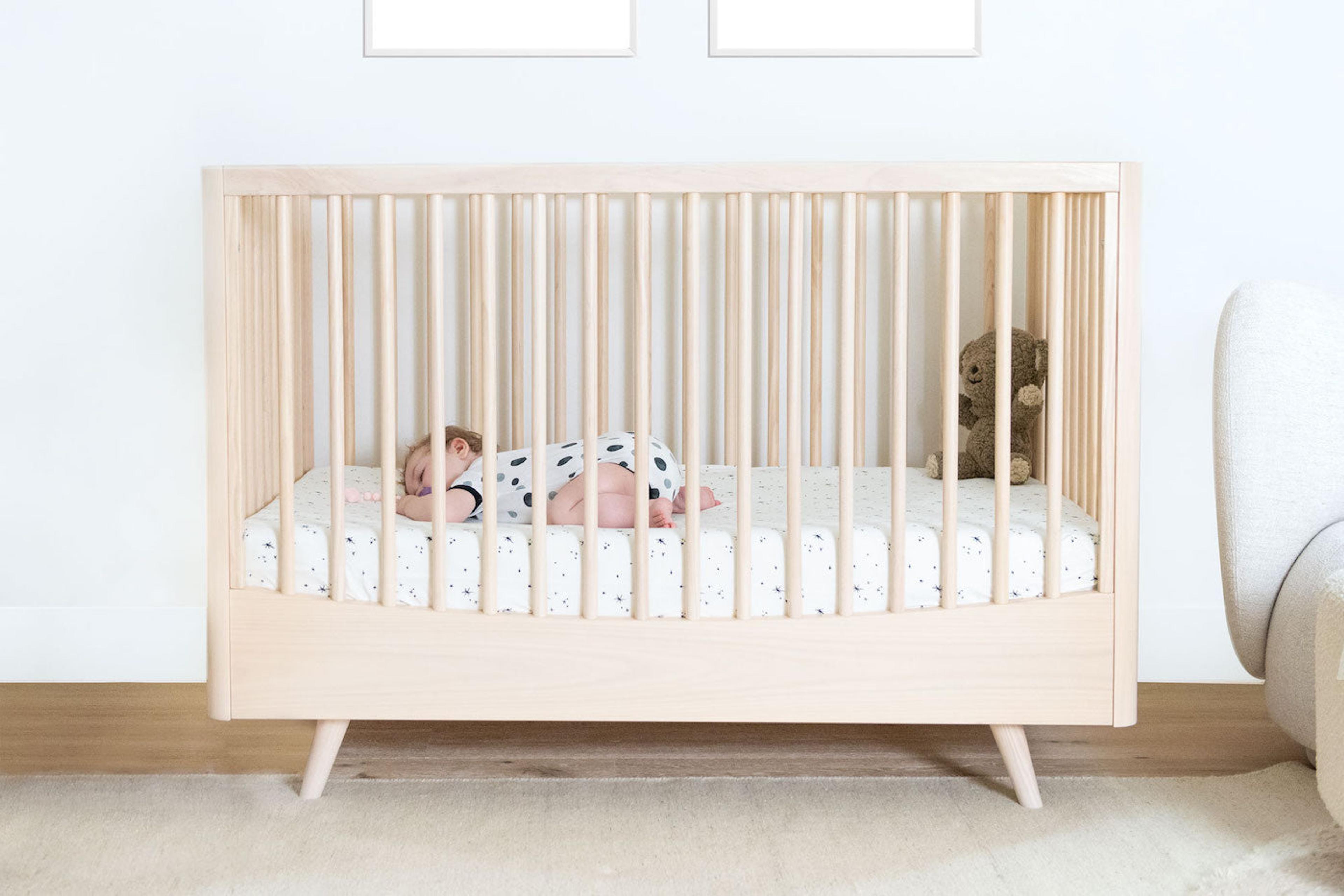 A baby sleeping on a crib sheet