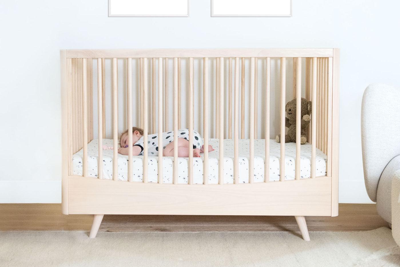 A baby sleeping on a crib sheet