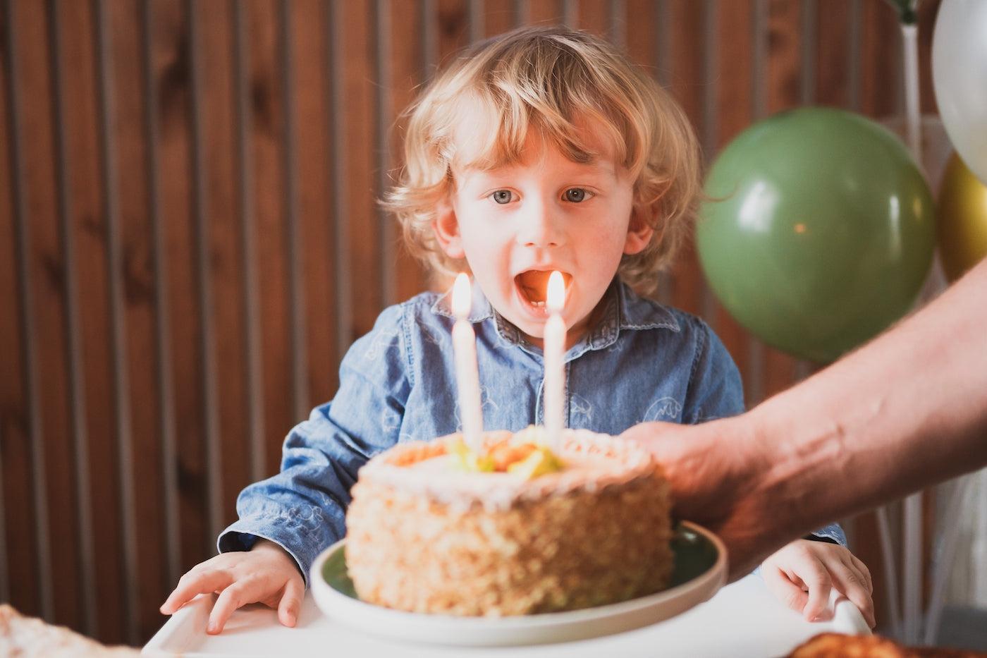 A two year old boy celebrates his birthday with cake