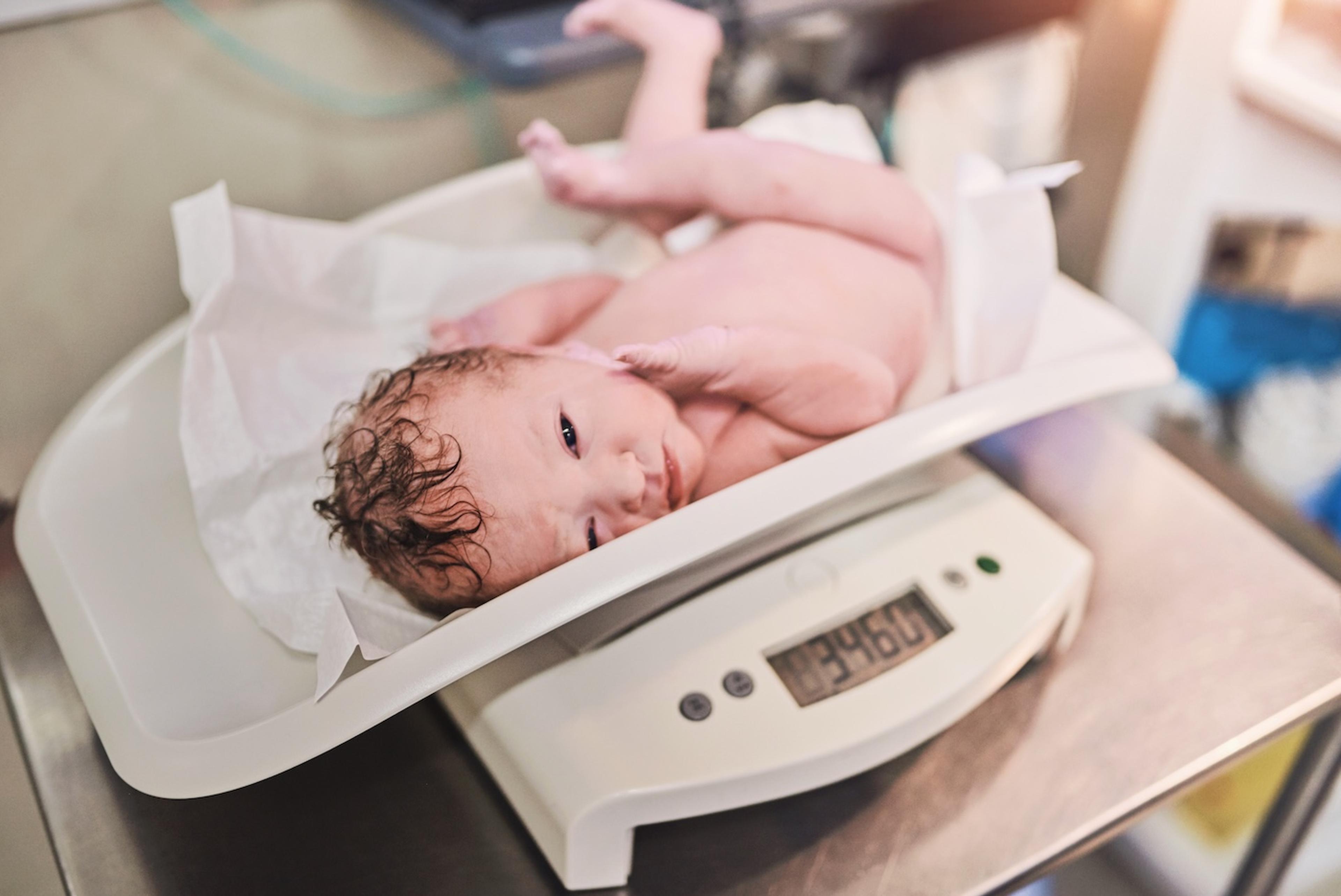 A newborn baby being weighed on a scale