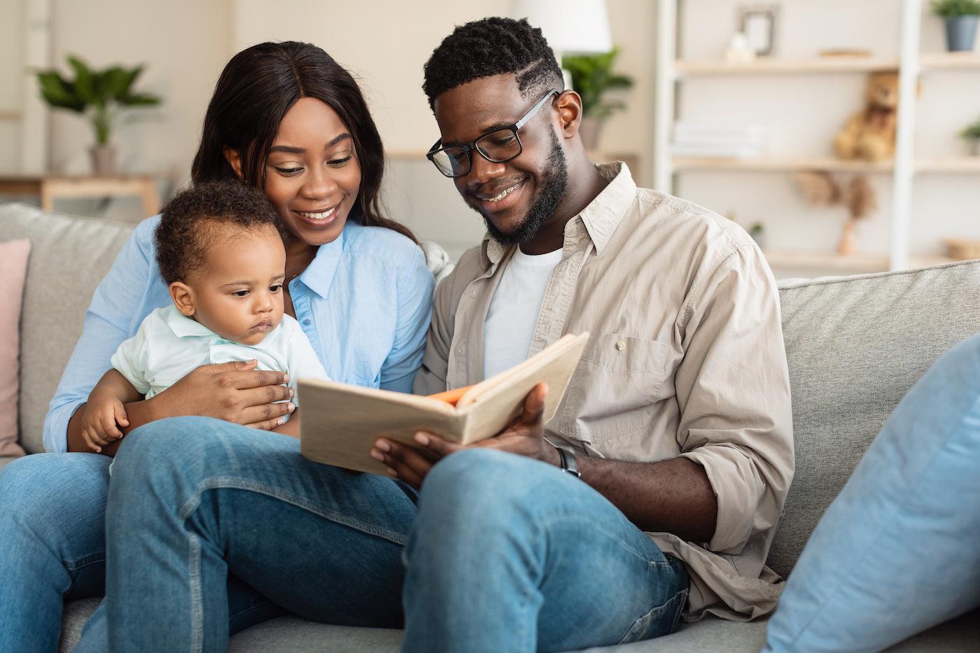 Parents read a baby book to their 6 month old baby