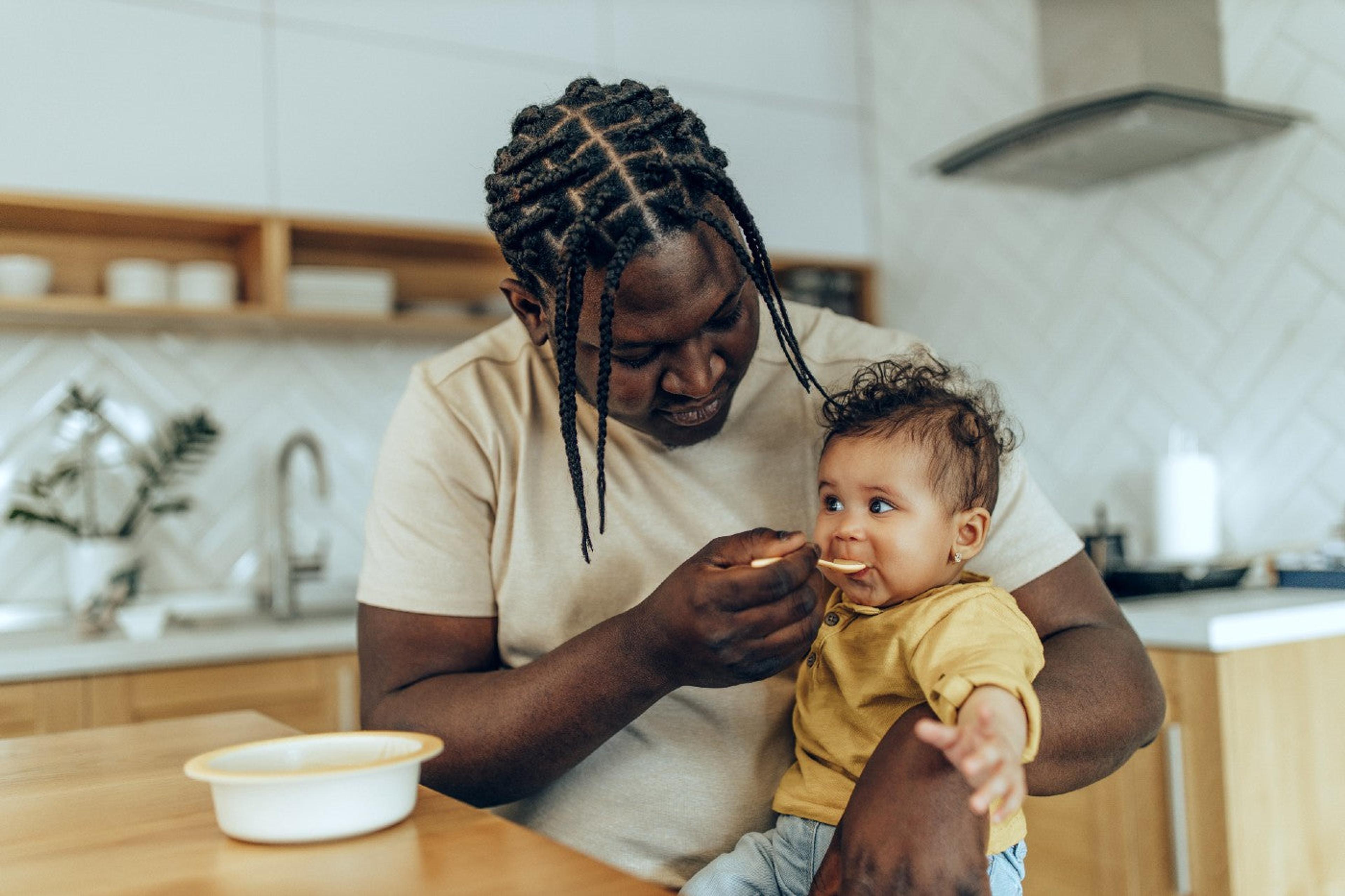 A father spoon feeds his baby daughter iron-rich oatmeal