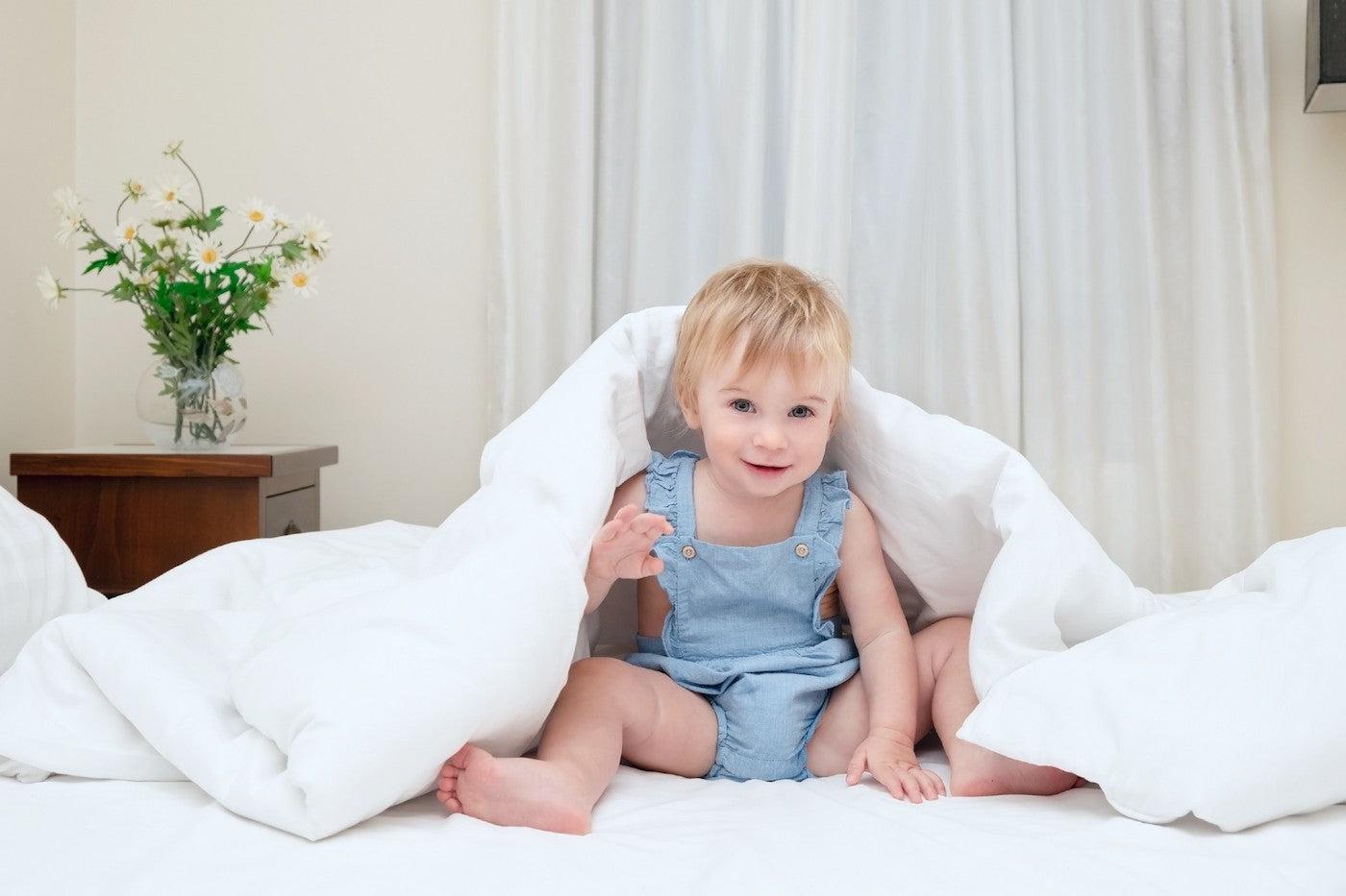 A 21-month-old baby playing in bed