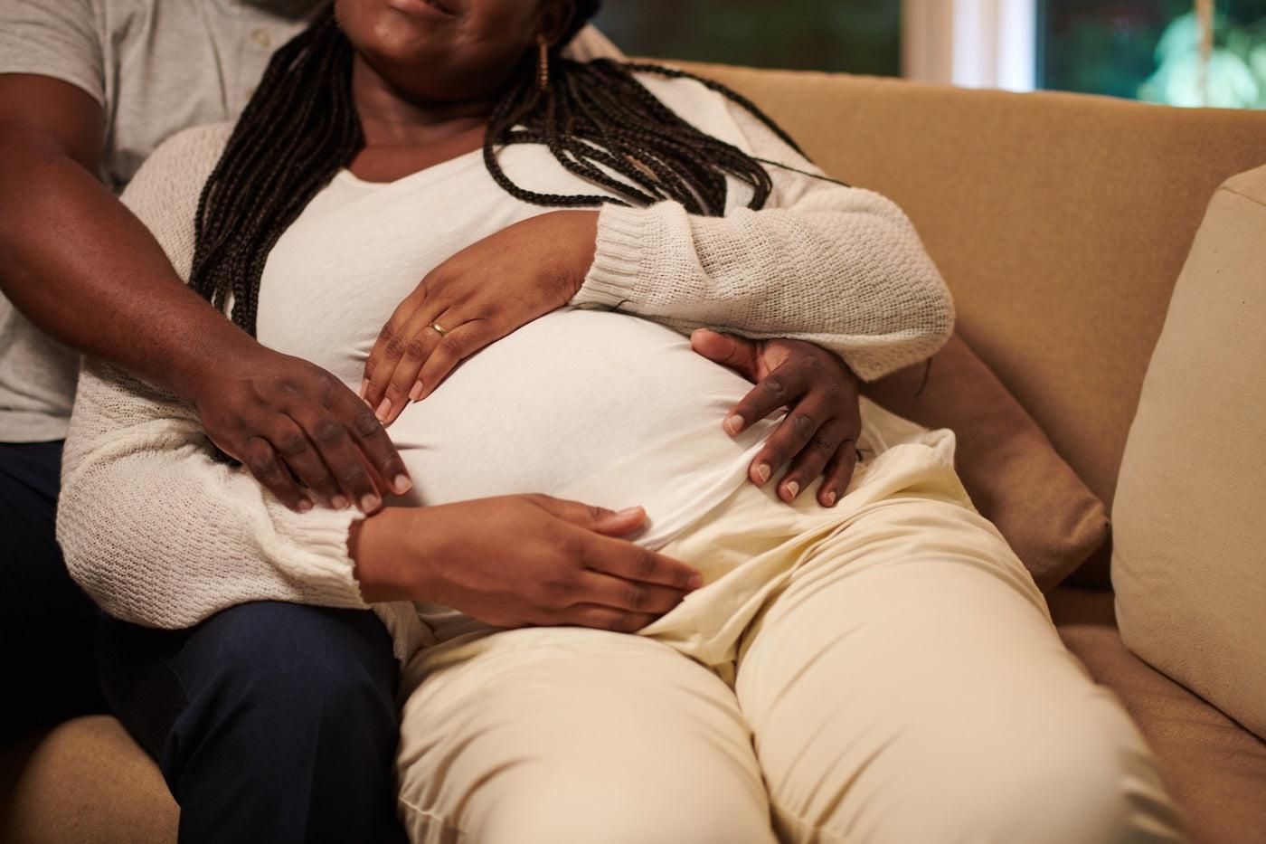 A Black man cuddles his pregnant wife