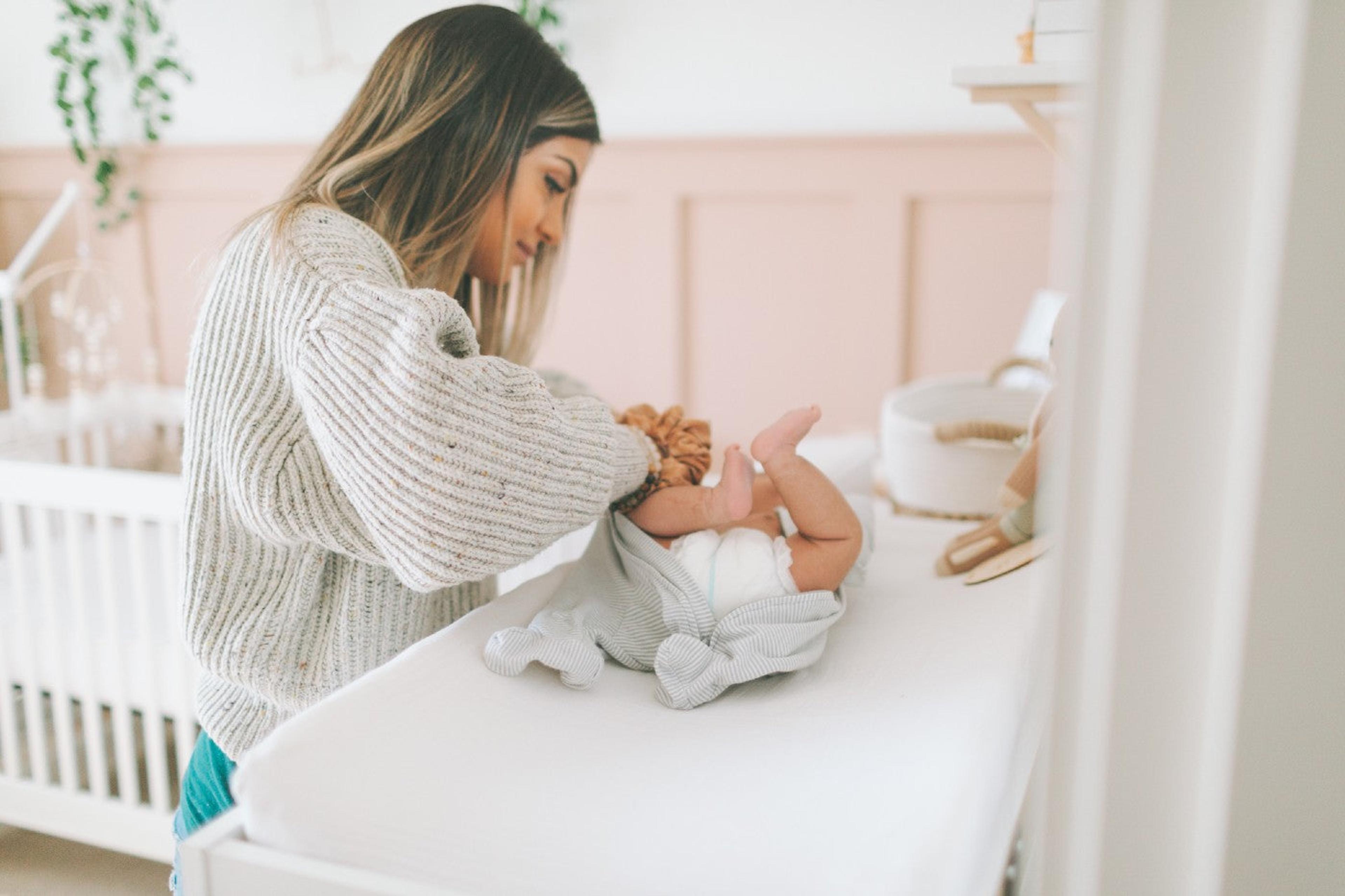 A mother changes her child's diaper on a changing table