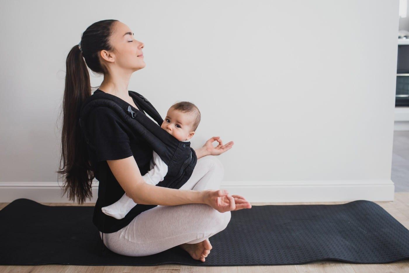 Mom practicing yoga while wearing her baby in a carrier