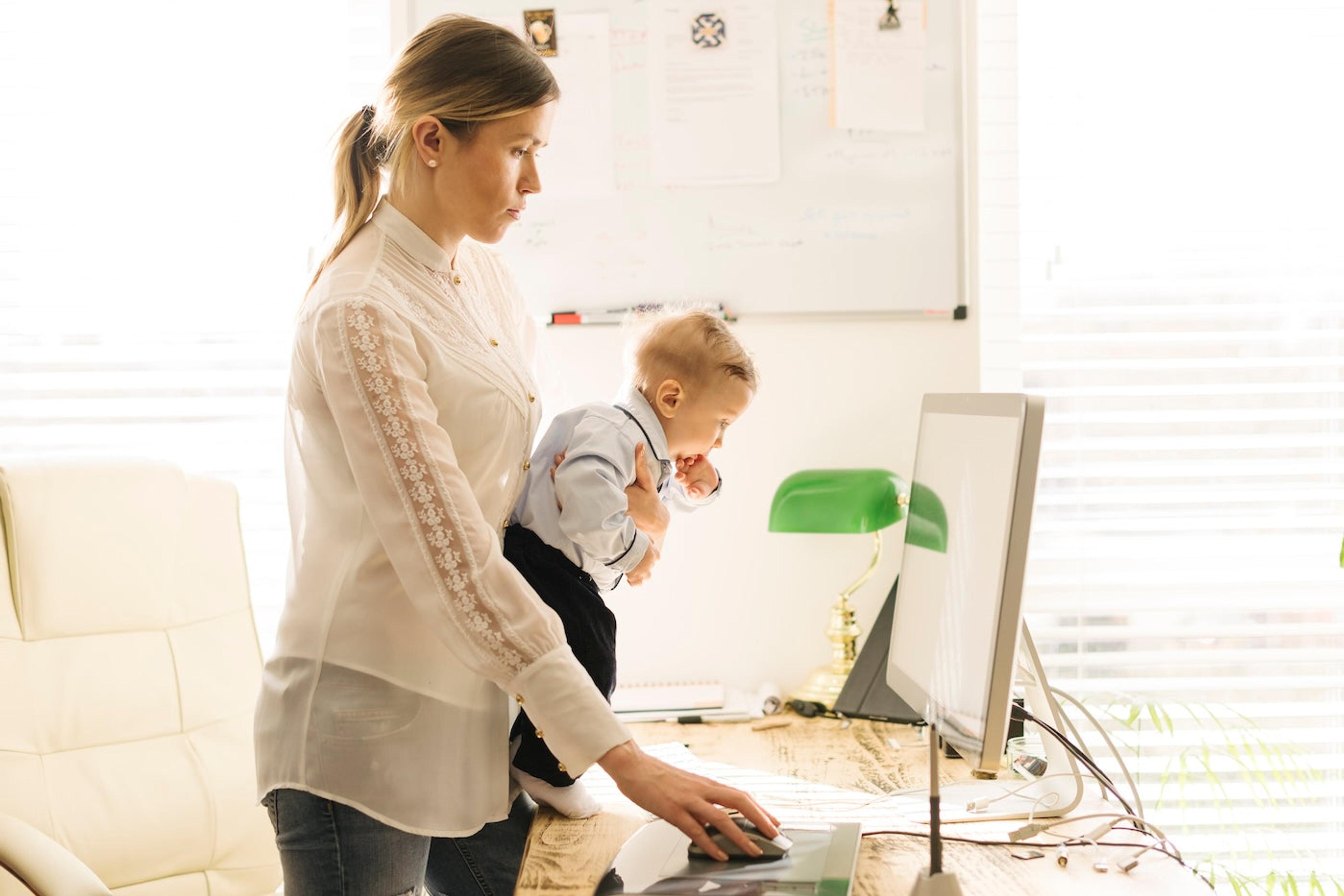 Mom working on a computer while holding her baby