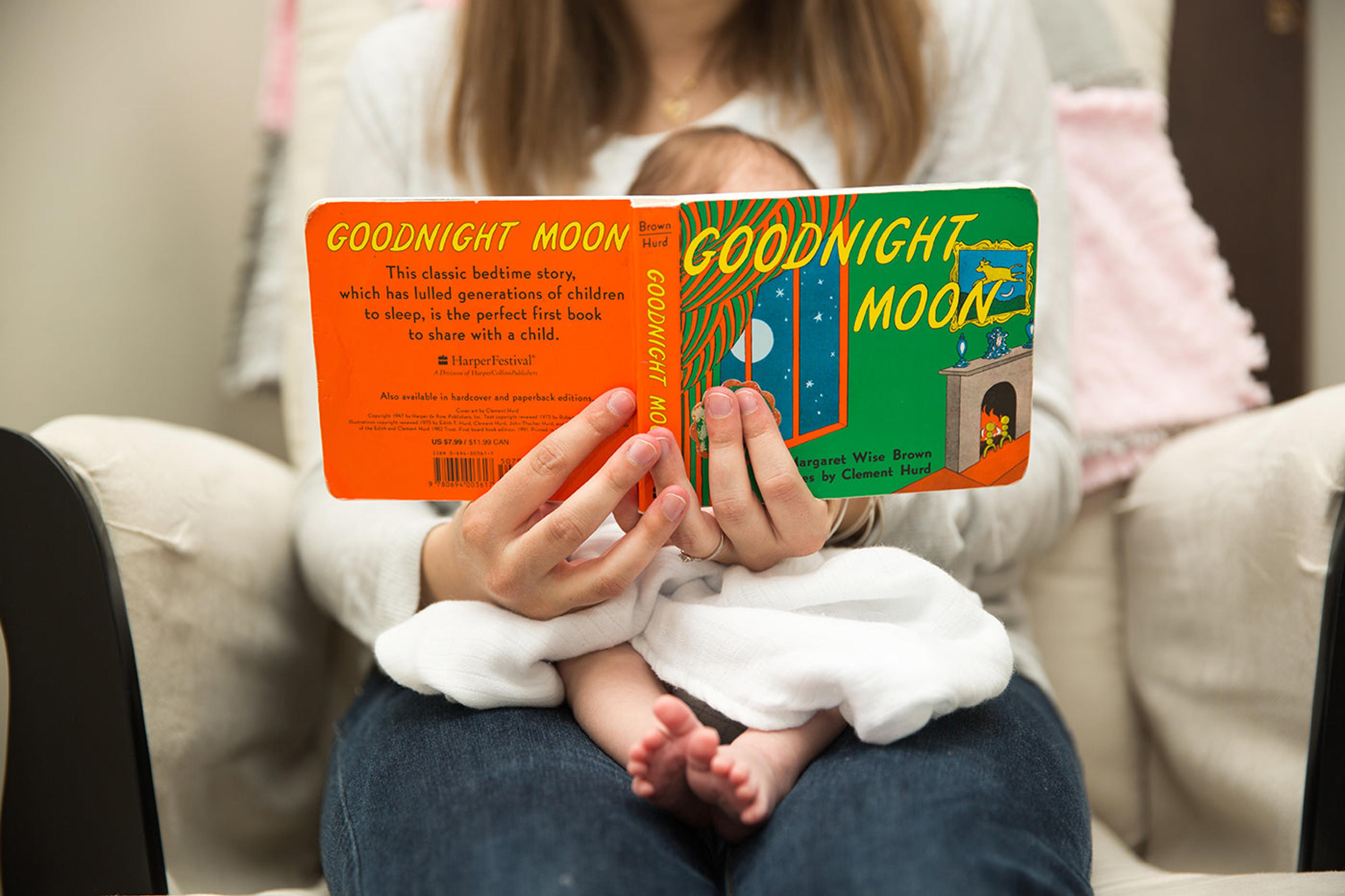 A mother reads "Goodnight Moon" to her baby