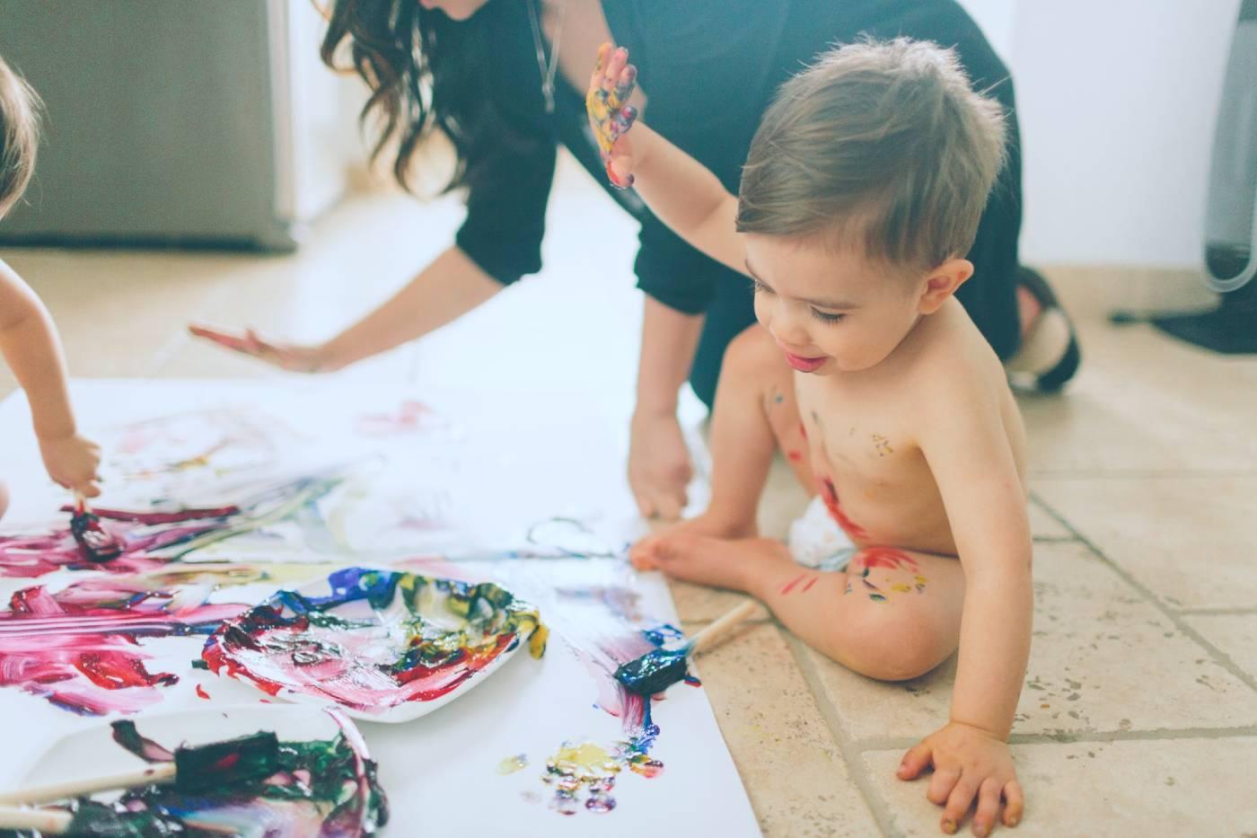Toddler finger painting on the floor.