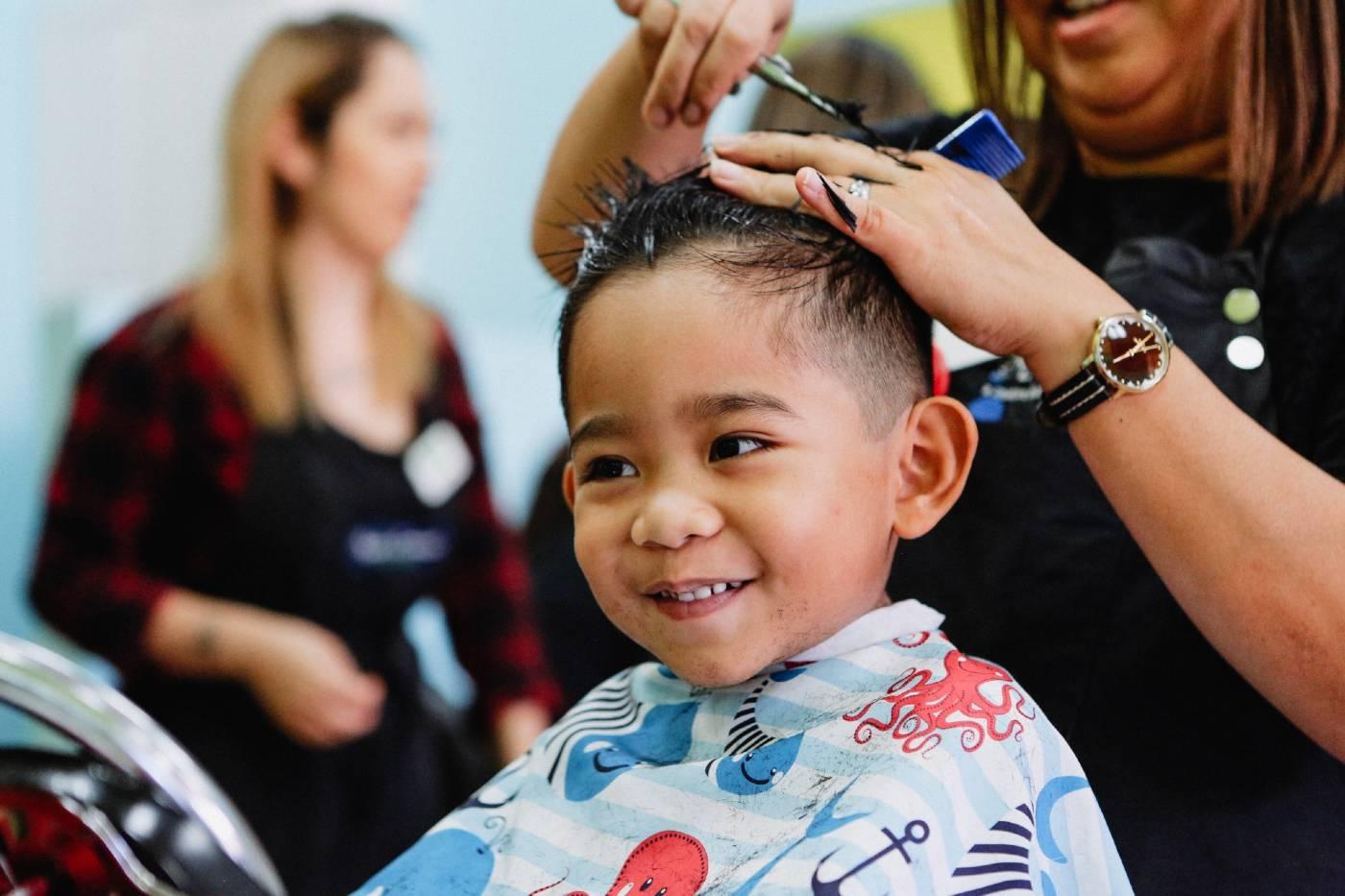 Toddler boy happily getting his first haircut