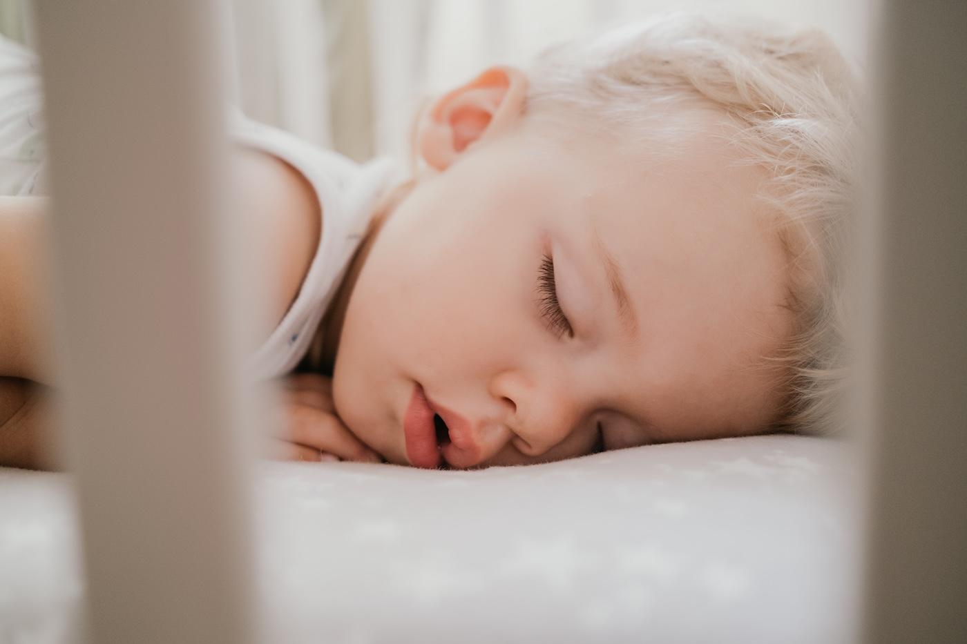A toddler sleeps in a crib