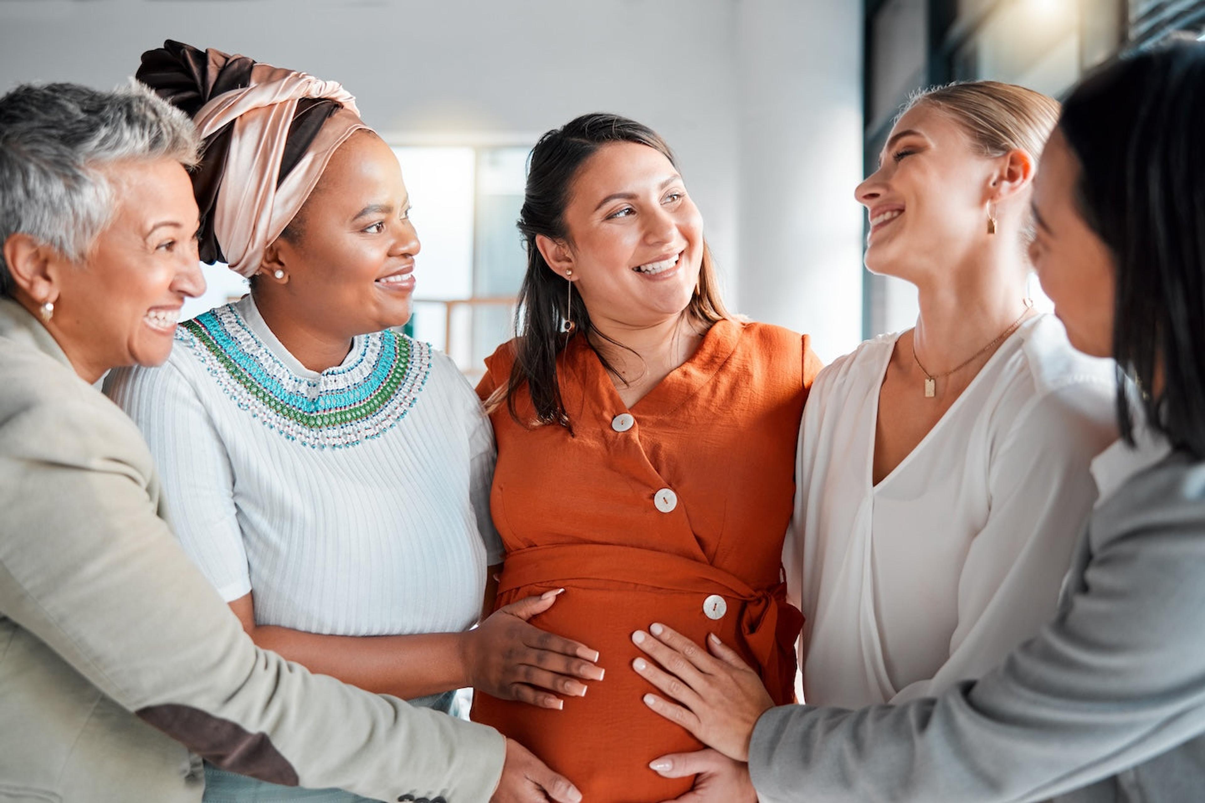 A group of women gathered around a pregnant woman at a nesting shower