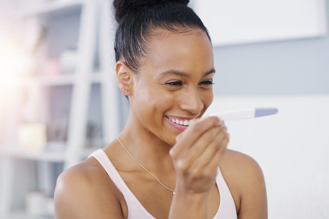 Woman looks happily at positive pregnancy test