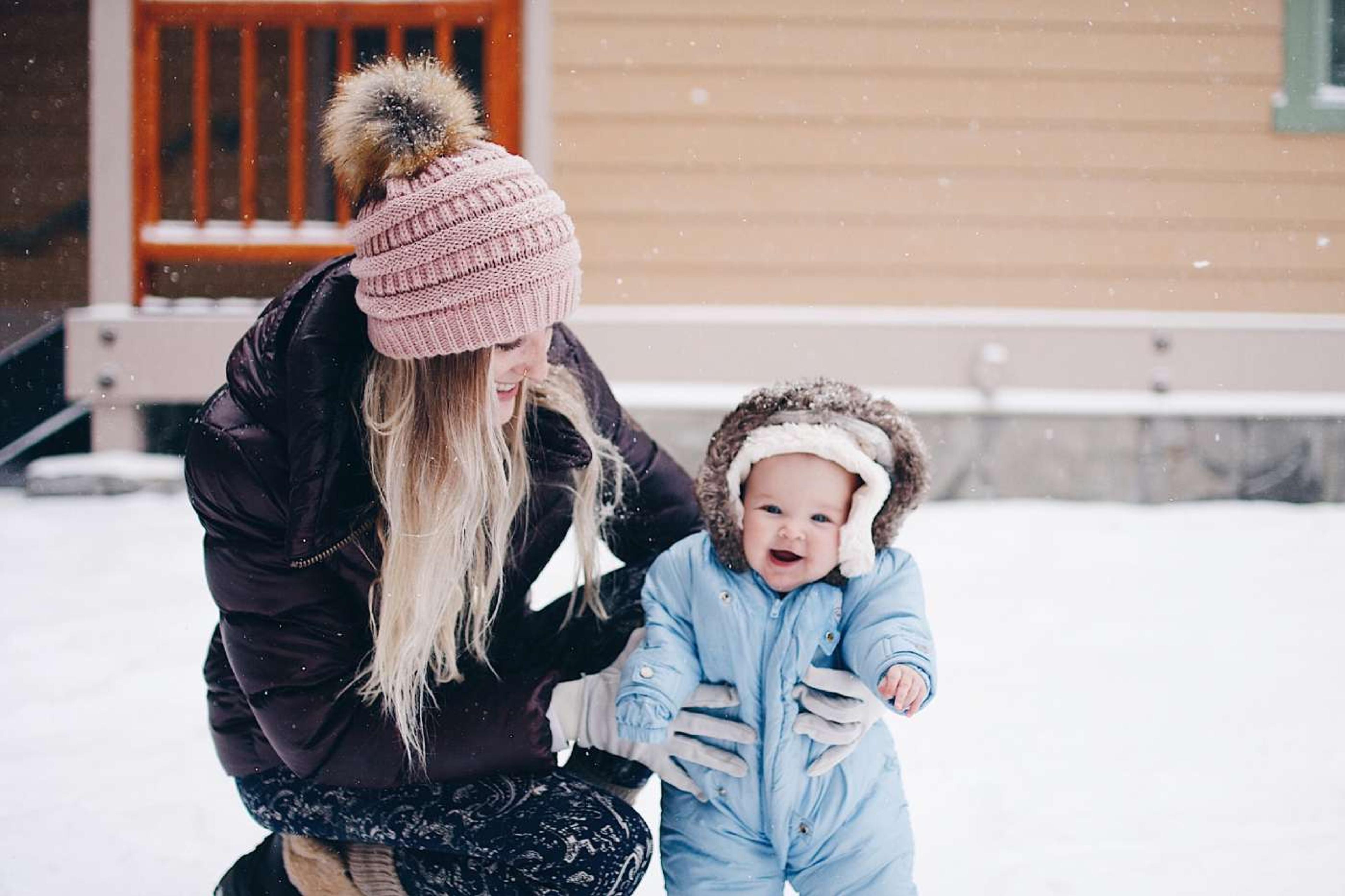 Cold weather tips for babies and toddlers - bundled up baby playing in snow with momr