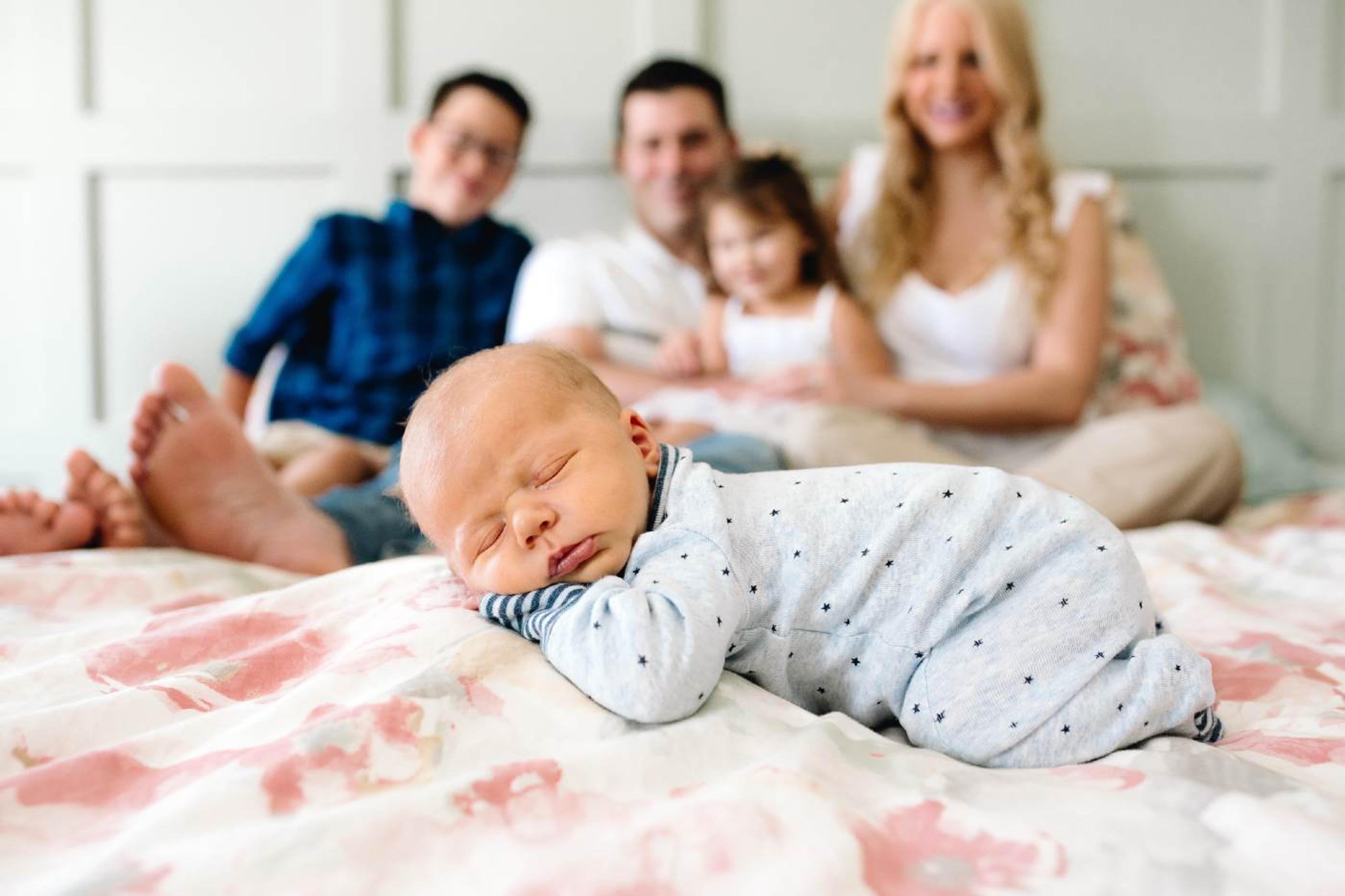 Baby sleeping in front of family on bed