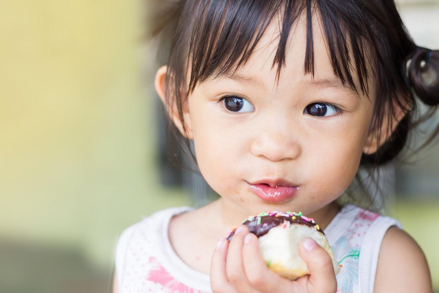 A 2-year-old toddler eats a birthday treat
