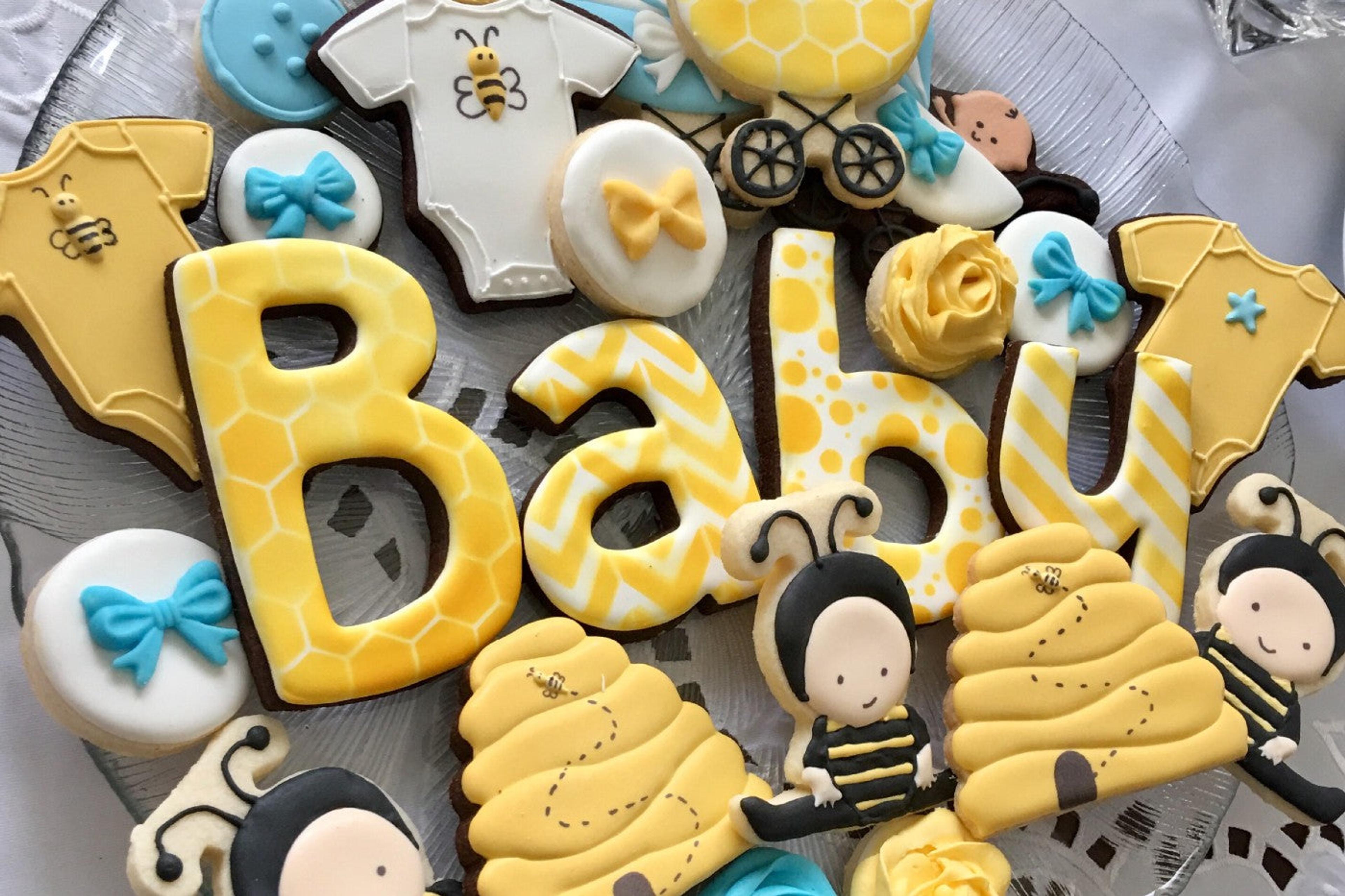 Yellow baby shower cookies shaped like bees, beehives, and the letters BABY