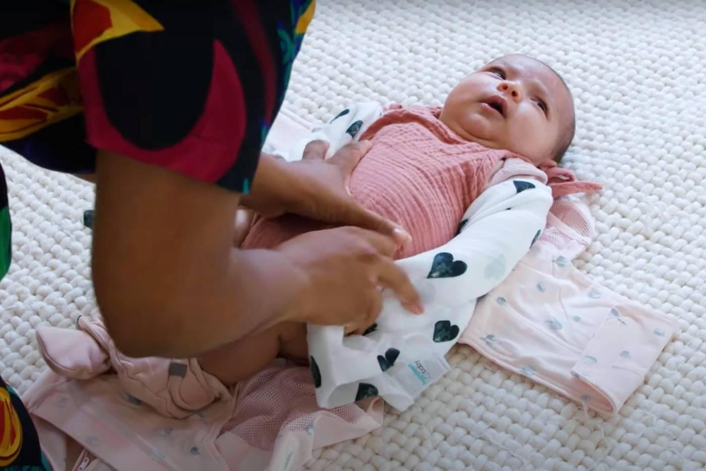 A caregiver double swaddles her baby in her SNOO Sack swaddle