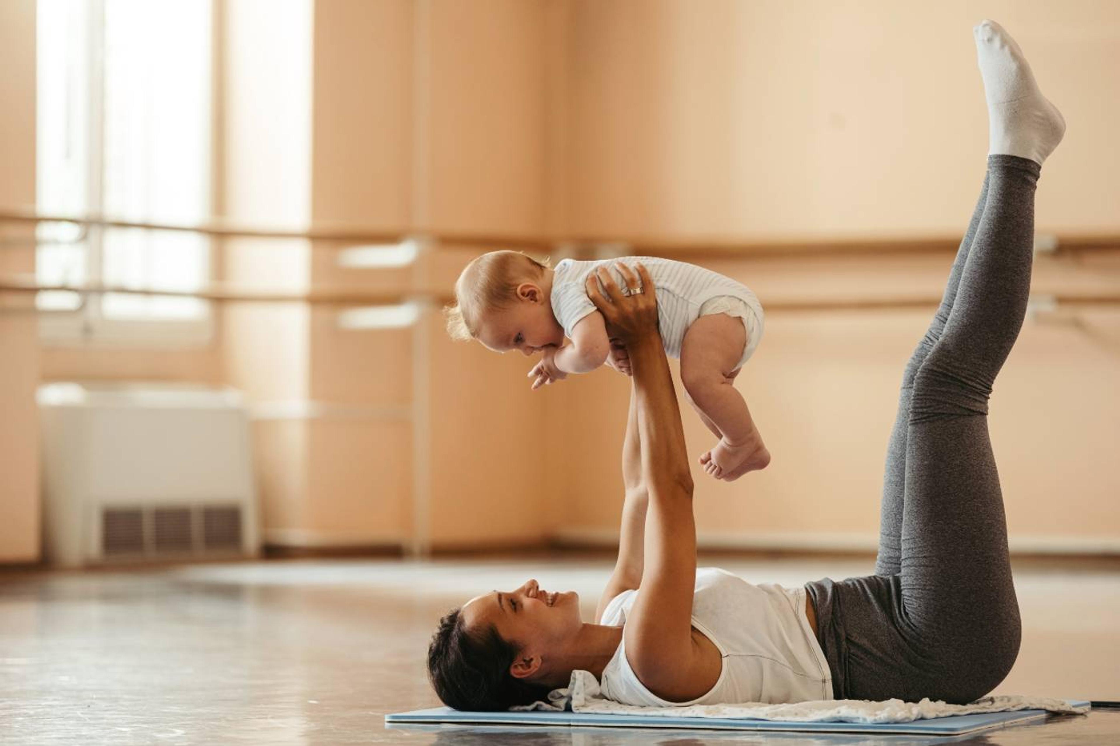 Mother doing yoga poses while holding a baby